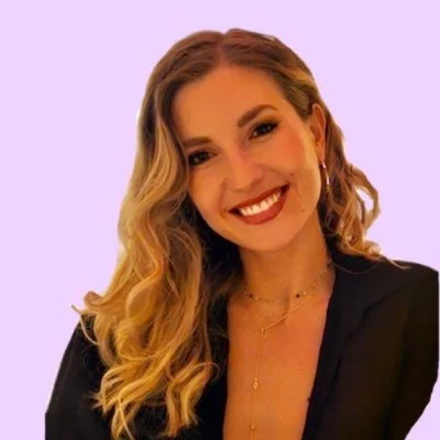 Mujer sonriendo con cabello rubio y rizado, fondo lila.