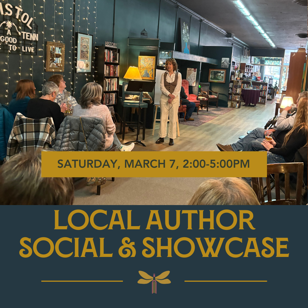 A view of a large room with a white woman wearing a cream shirt and pants and a brown vest talking in front of an audience.