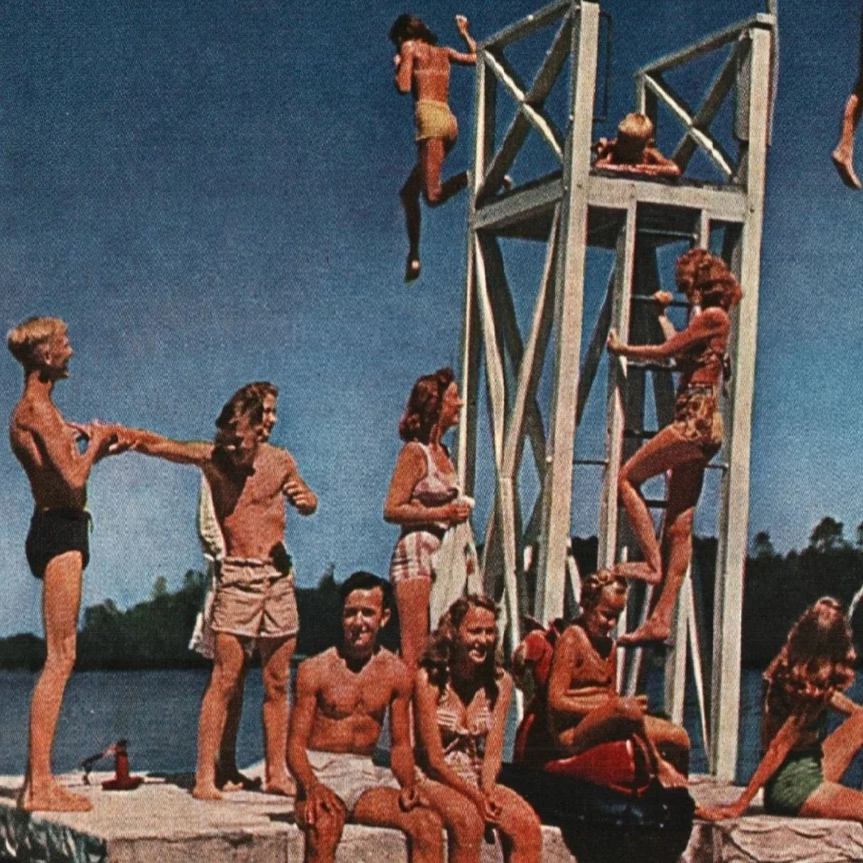 People enjoying a day at a lake with a diving platform. Some are climbing or diving off the platform, while others are sunbathing. Text reads "The Water's Warm."