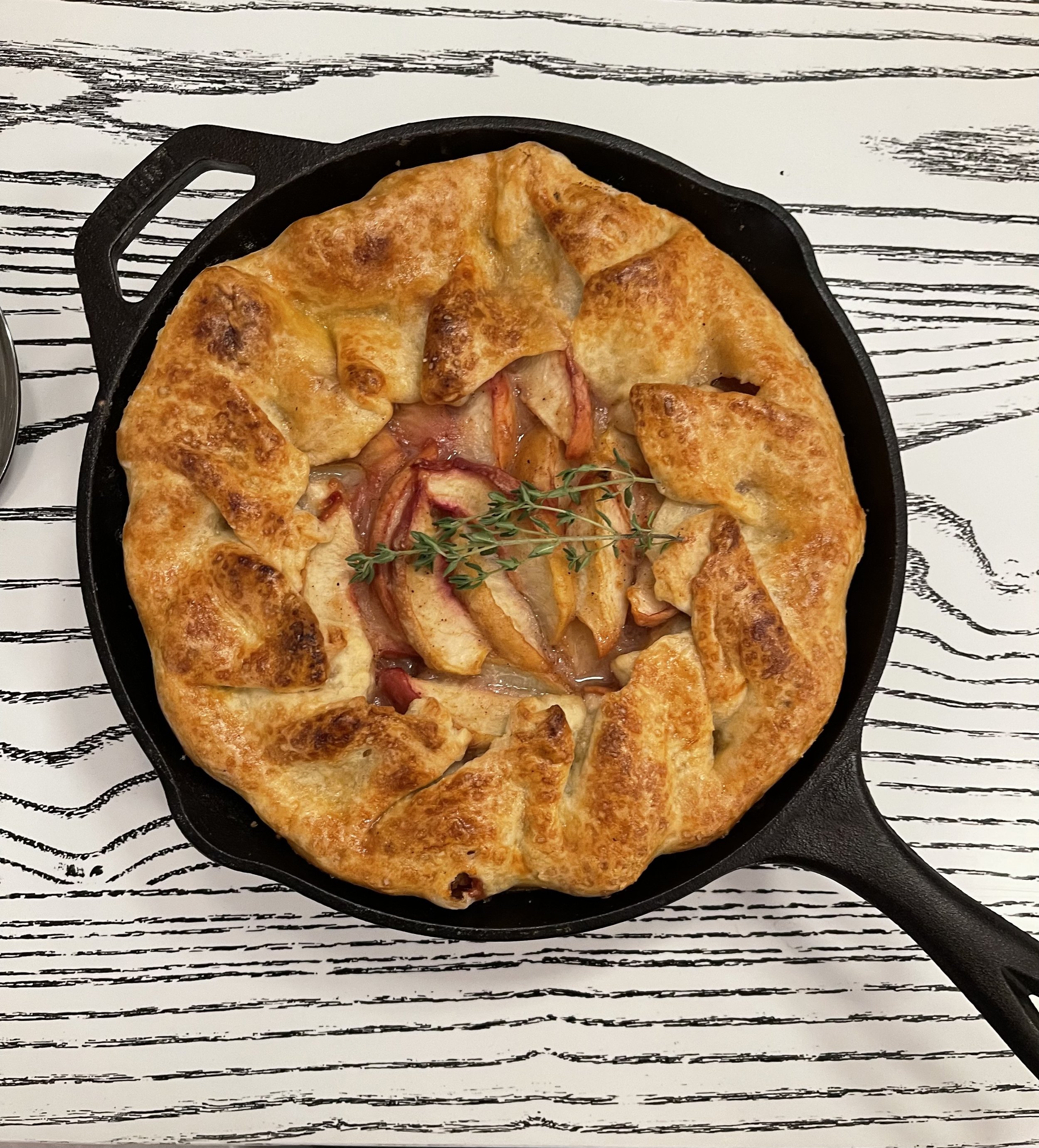 Rustic fruit galette in a cast iron skillet on a textured surface