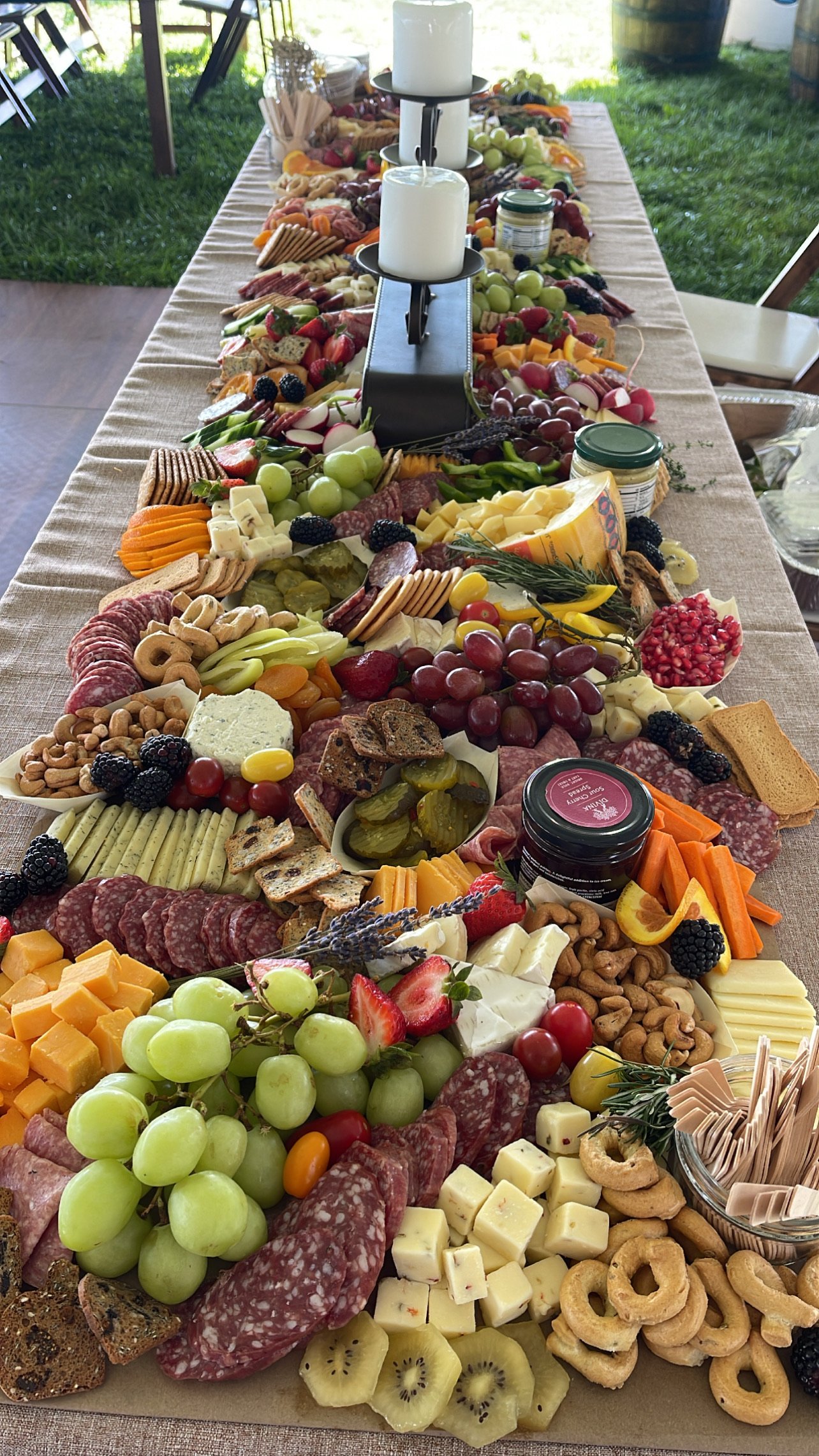 Grazing table with assorted cheeses, meats, fruits, vegetables, nuts, crackers, and dips.
