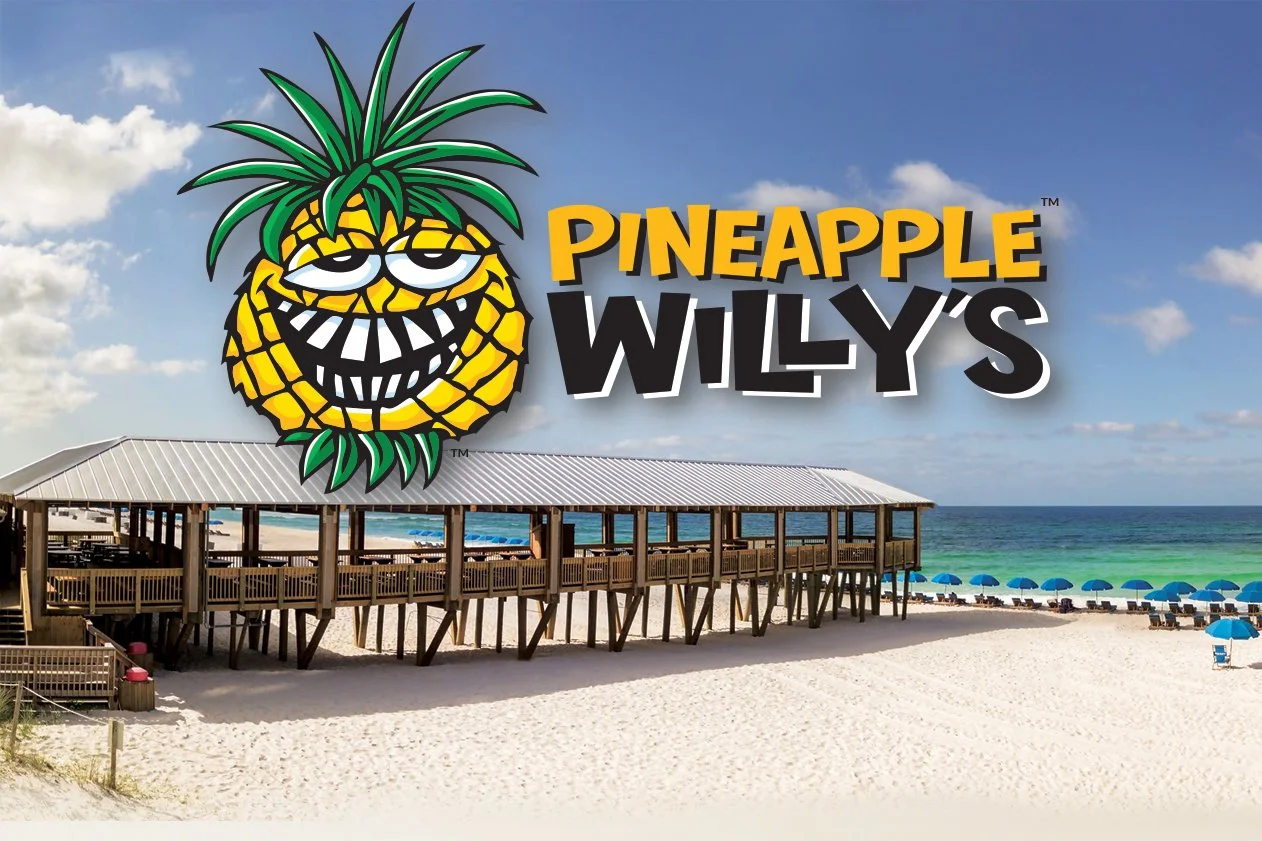 Image of Pineapple Willy's restaurant's covered pier that goes out on the sand, the ocean is in the background.