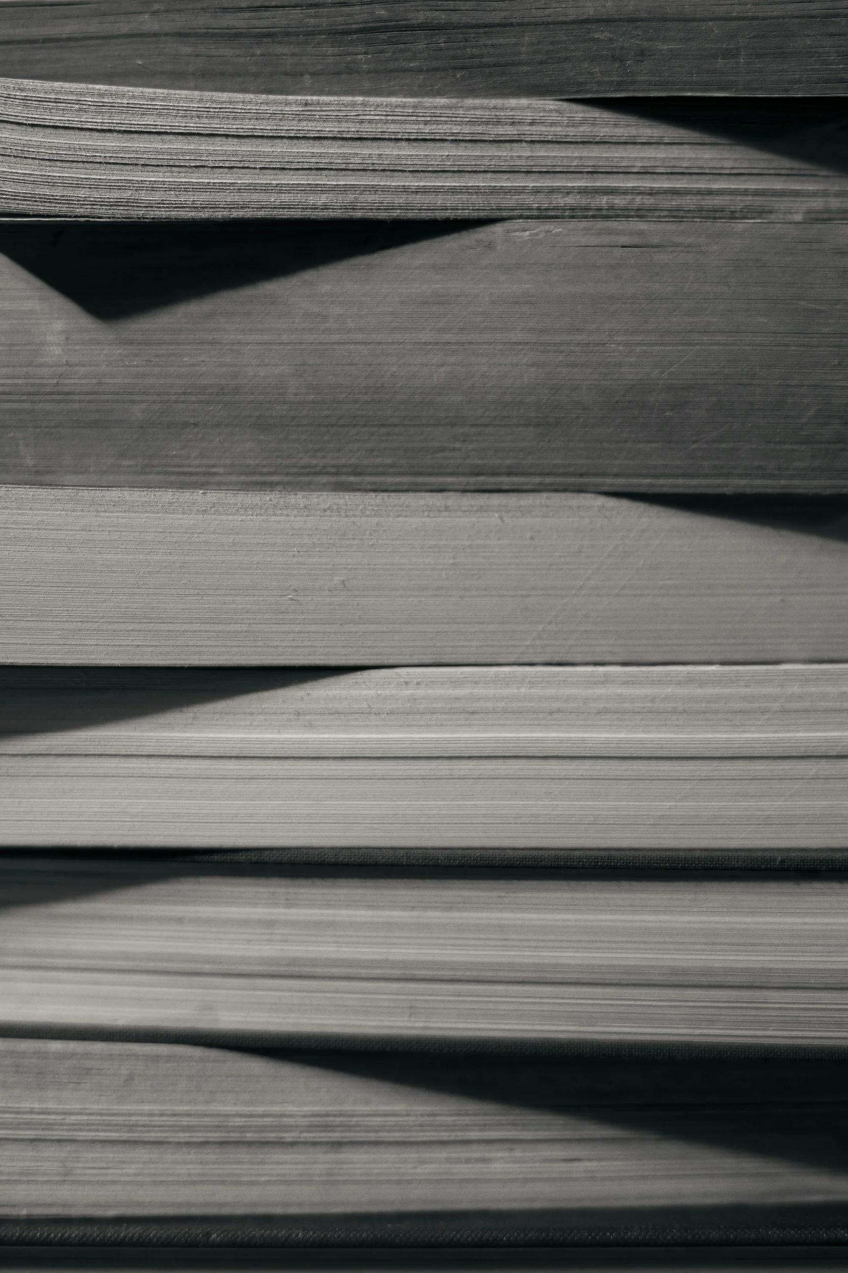 Close-up view of a stack of black and white paper sheets, with some sheets slightly misaligned, creating shadows and lines.