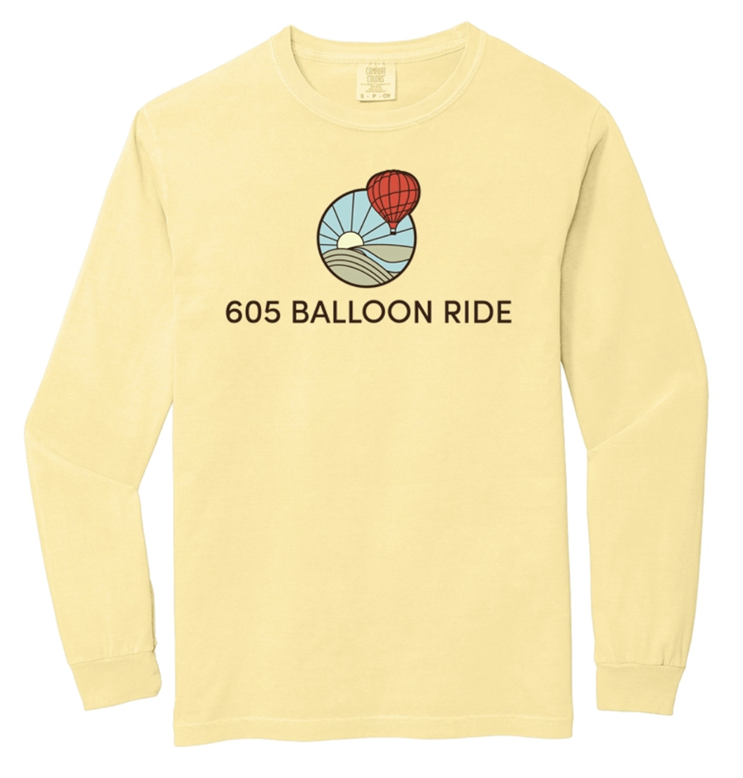 Yellow long-sleeve shirt with a graphic of a hot air balloon flying over hills and a sun, and the text "605 Balloon Ride" below the graphic.