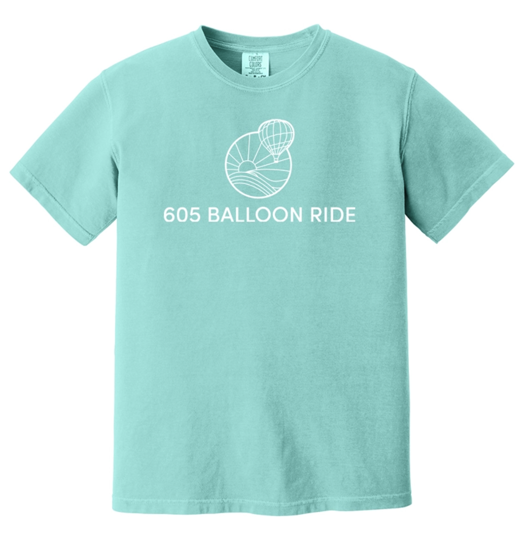 Light blue T-shirt with a white graphic of a hot air balloon and a sun or moon over wavy lines, and the text '605 Balloon Ride' underneath.