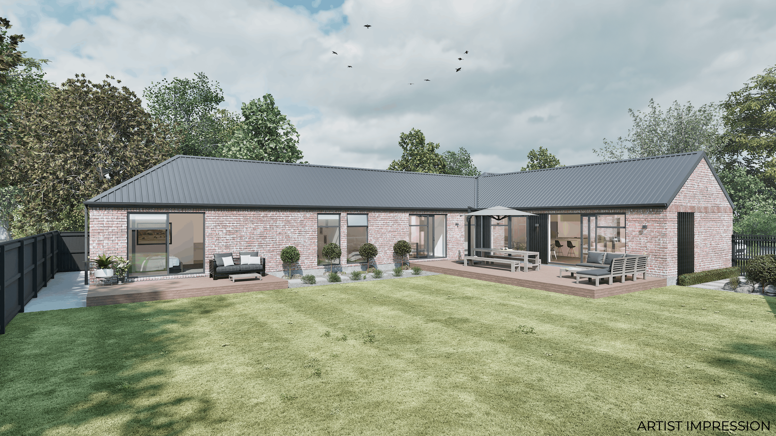 Modern brick house with a metal roof, two outdoor sitting areas with furniture, potted plants, and a fenced yard with a lawn and trees in the background under a cloudy sky.