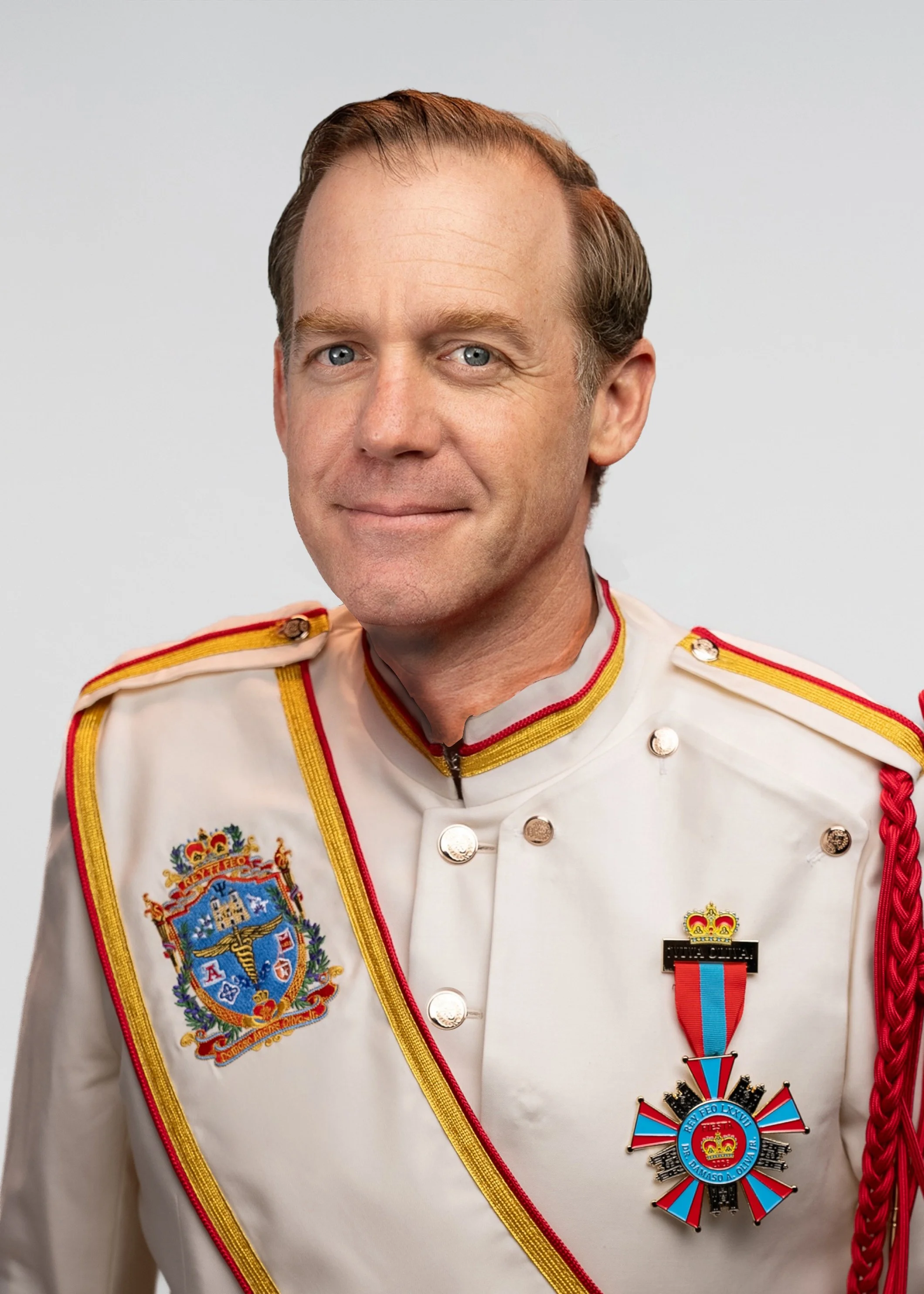 A middle-aged man with fair skin, blue eyes, and short, light brown hair, wearing a red collared shirt, looking at the camera with a slight smile, against a gray background.