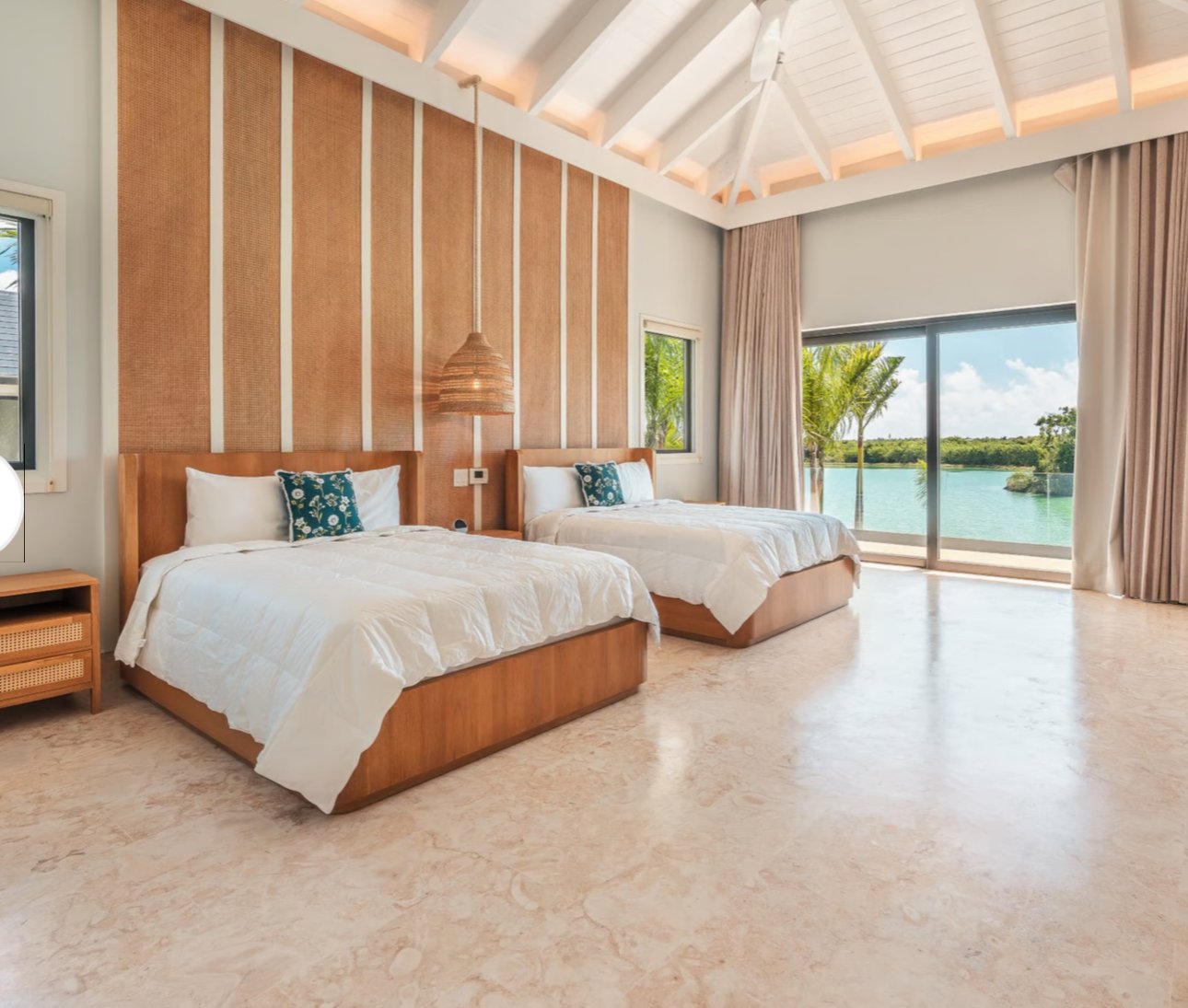 Spacious bedroom with two beds, wood paneling, large windows offering scenic lake view, and modern decor.