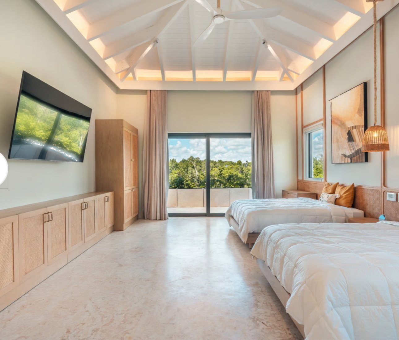 Spacious modern bedroom with large windows, high ceiling, two beds, wall-mounted TV, wooden furniture, and a scenic outdoor view.