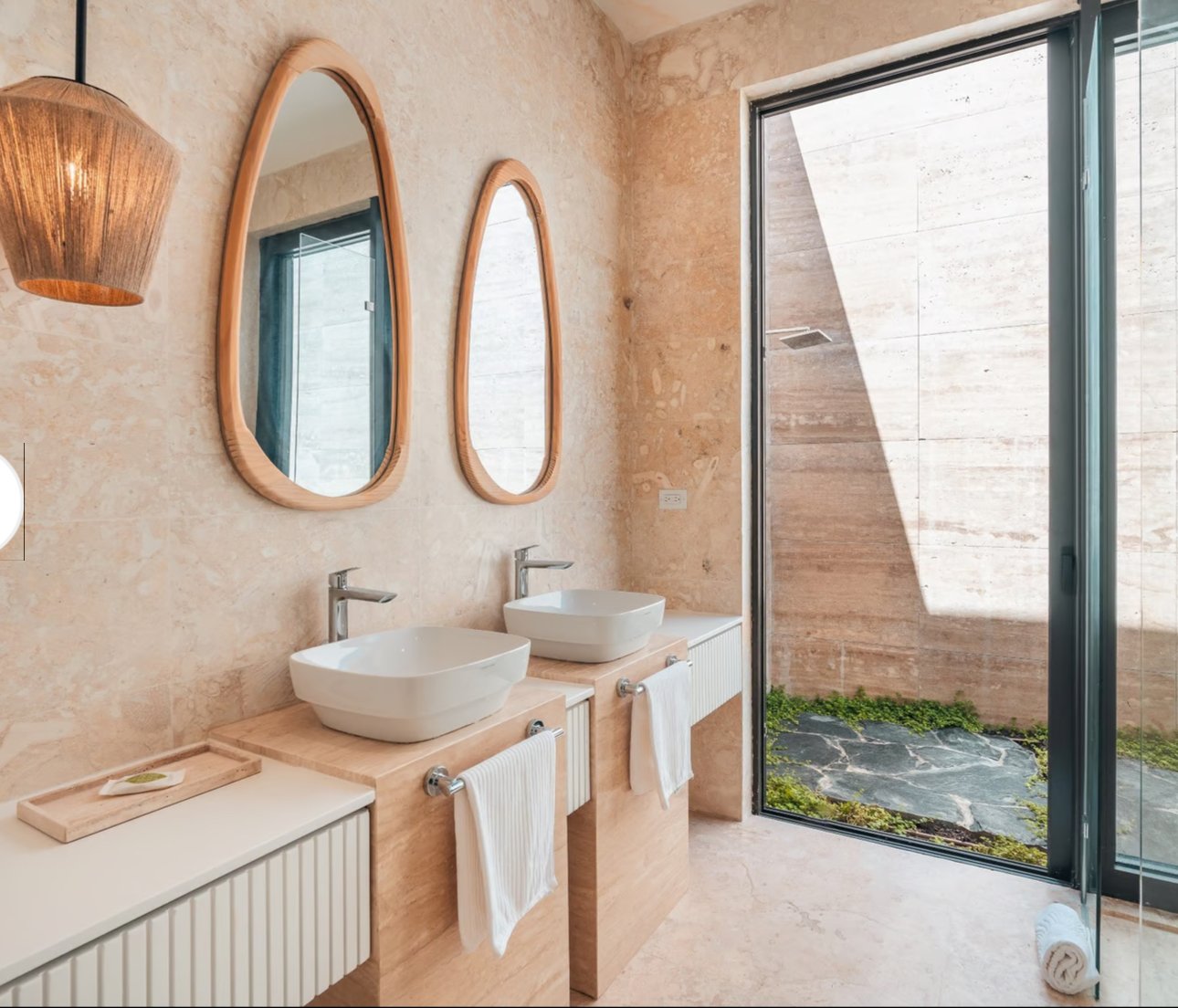 Modern bathroom with two sinks and oval mirrors, featuring a large window and minimalist decor.