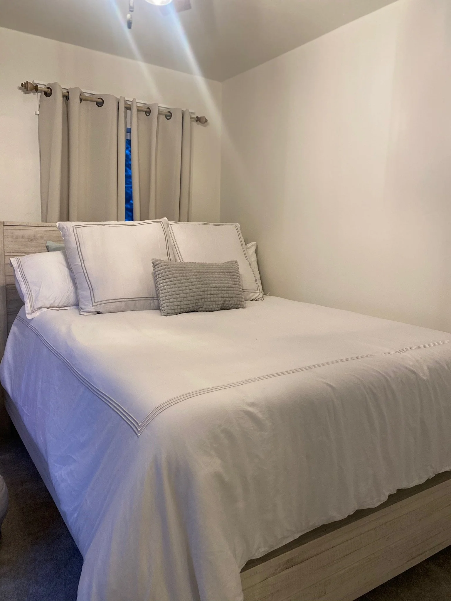 Bedroom with white bedding and beige curtains