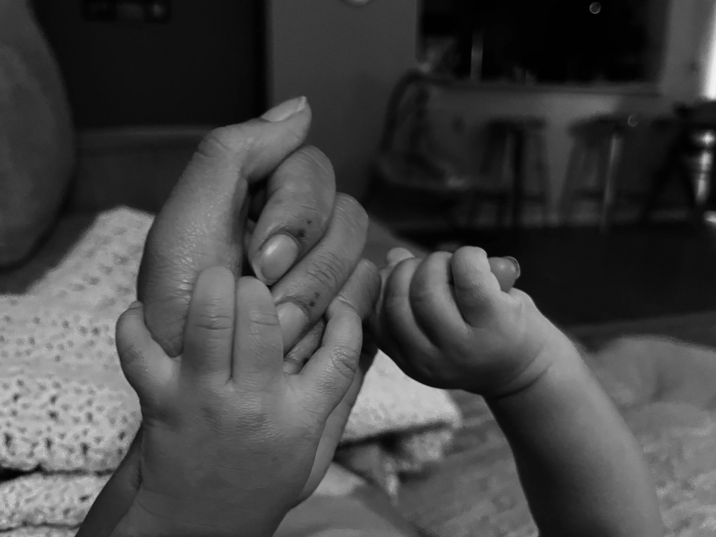Close-up of an adult hand holding a child's hand, in black and white.