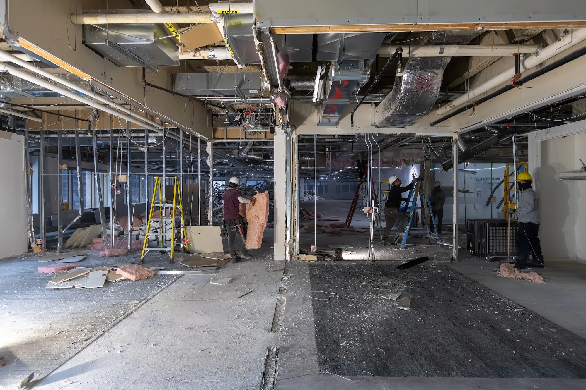 Westrose Construction crew performing full commercial demolition and gut renovation at 121 King Street Toronto, with workers removing insulation and wall framing