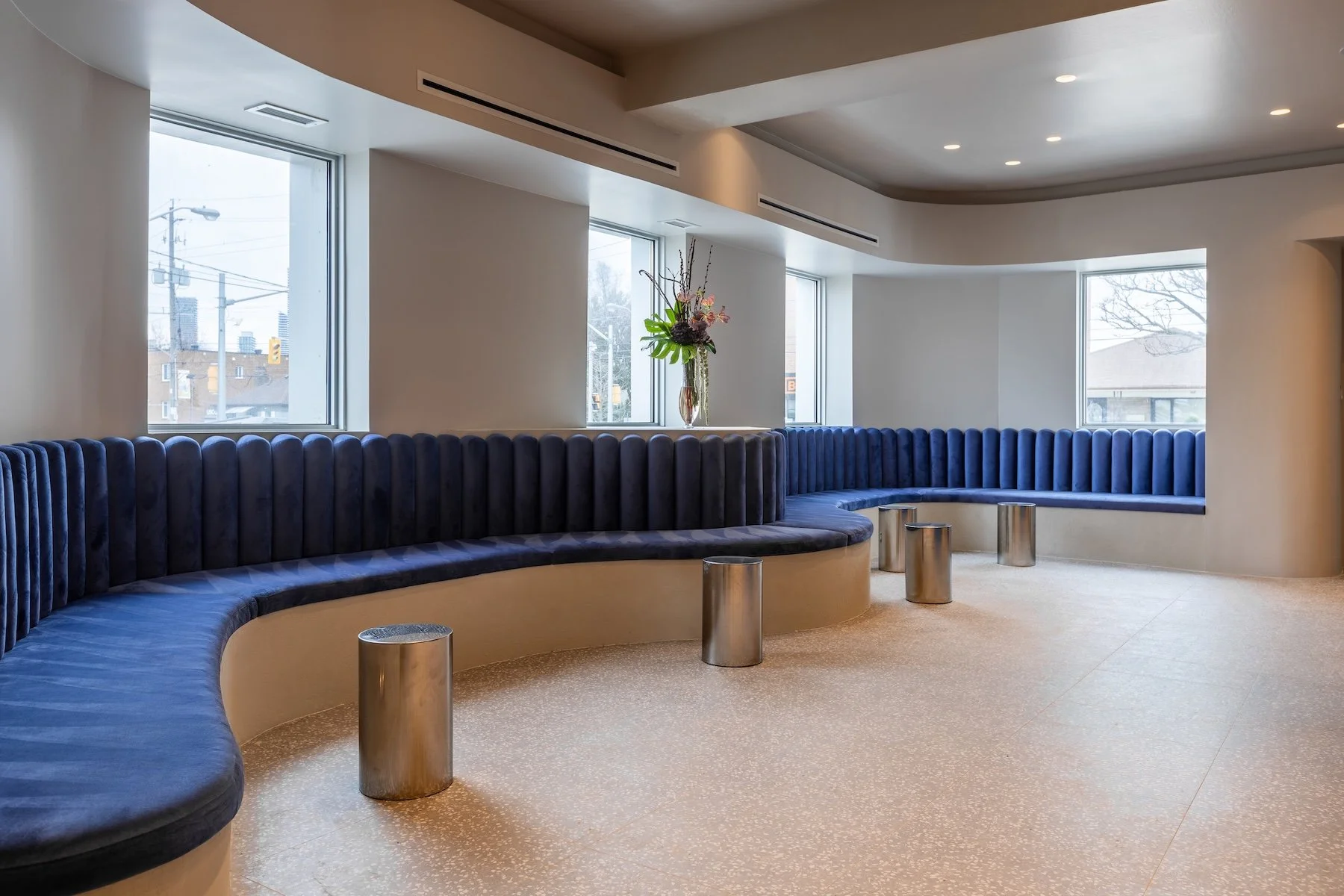 Curved blue velvet lounge seating with city view windows at Skinworthy Toronto commercial build