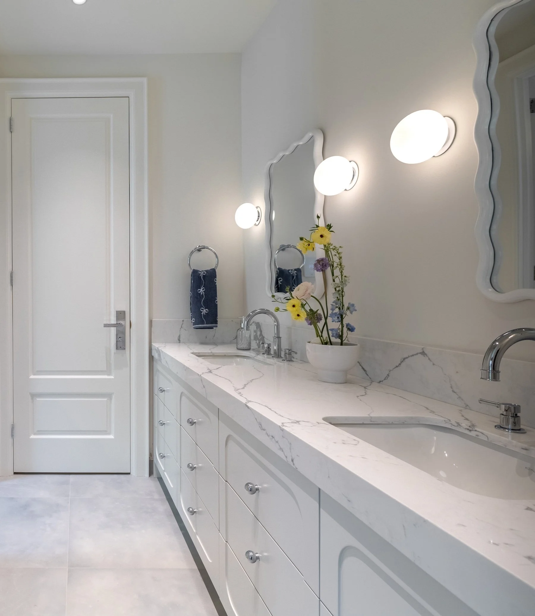 Double vanity bathroom with scalloped mirrors and globe sconces in Etobicoke home