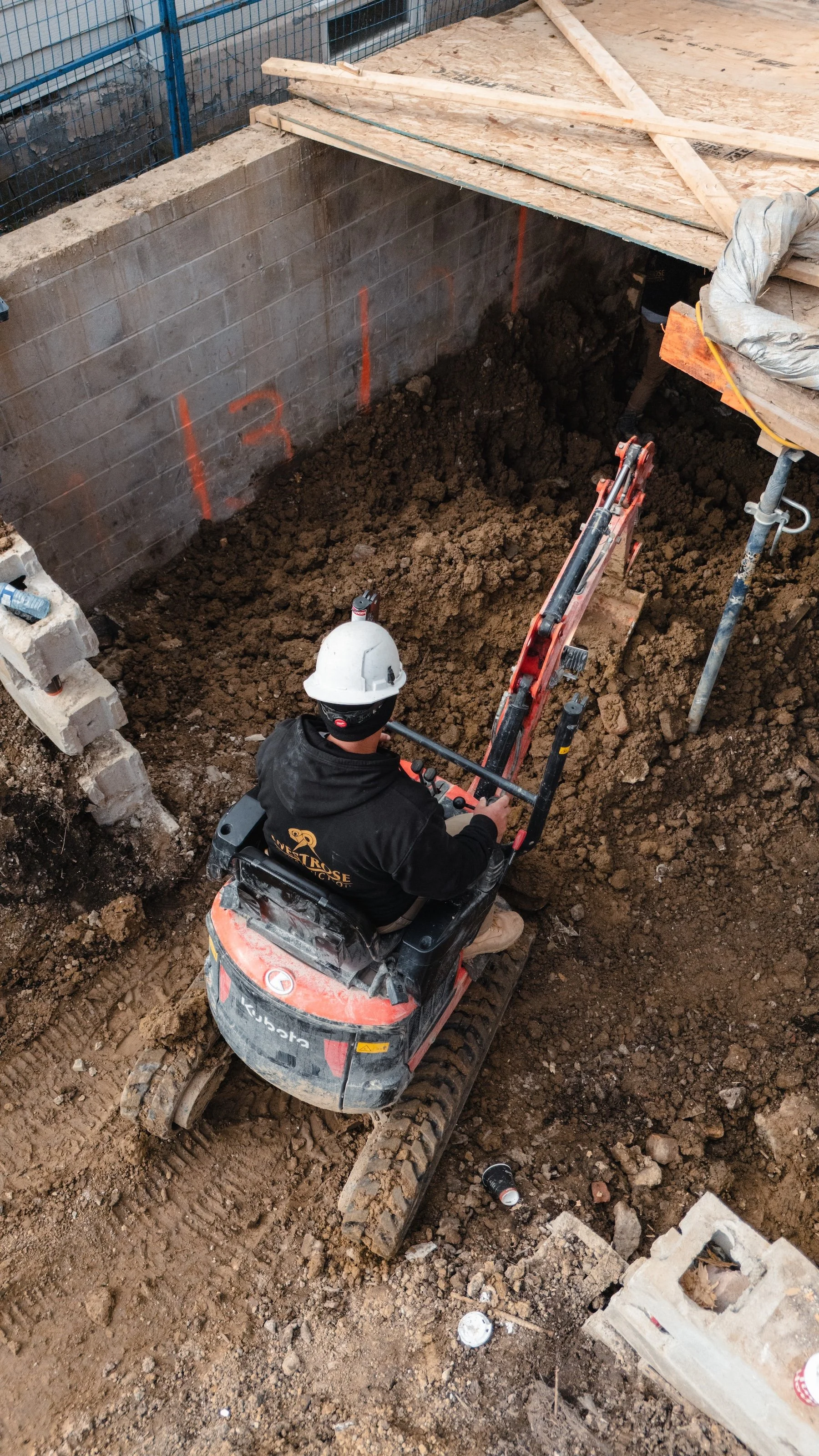 Worker excavating basement during underpinning and foundation lowering process