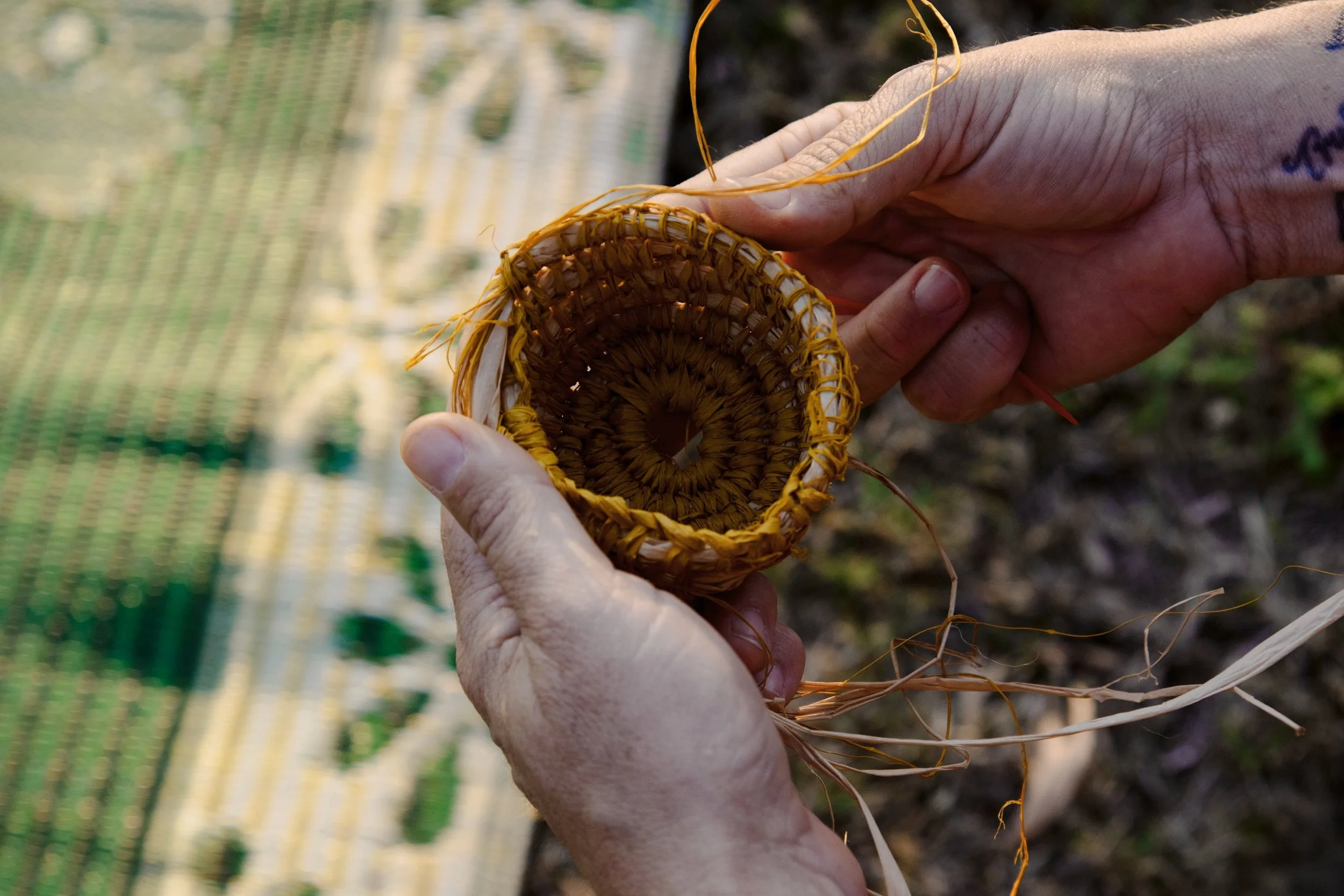 Close-up of hands holding a small woven basket made from natural fibers.
