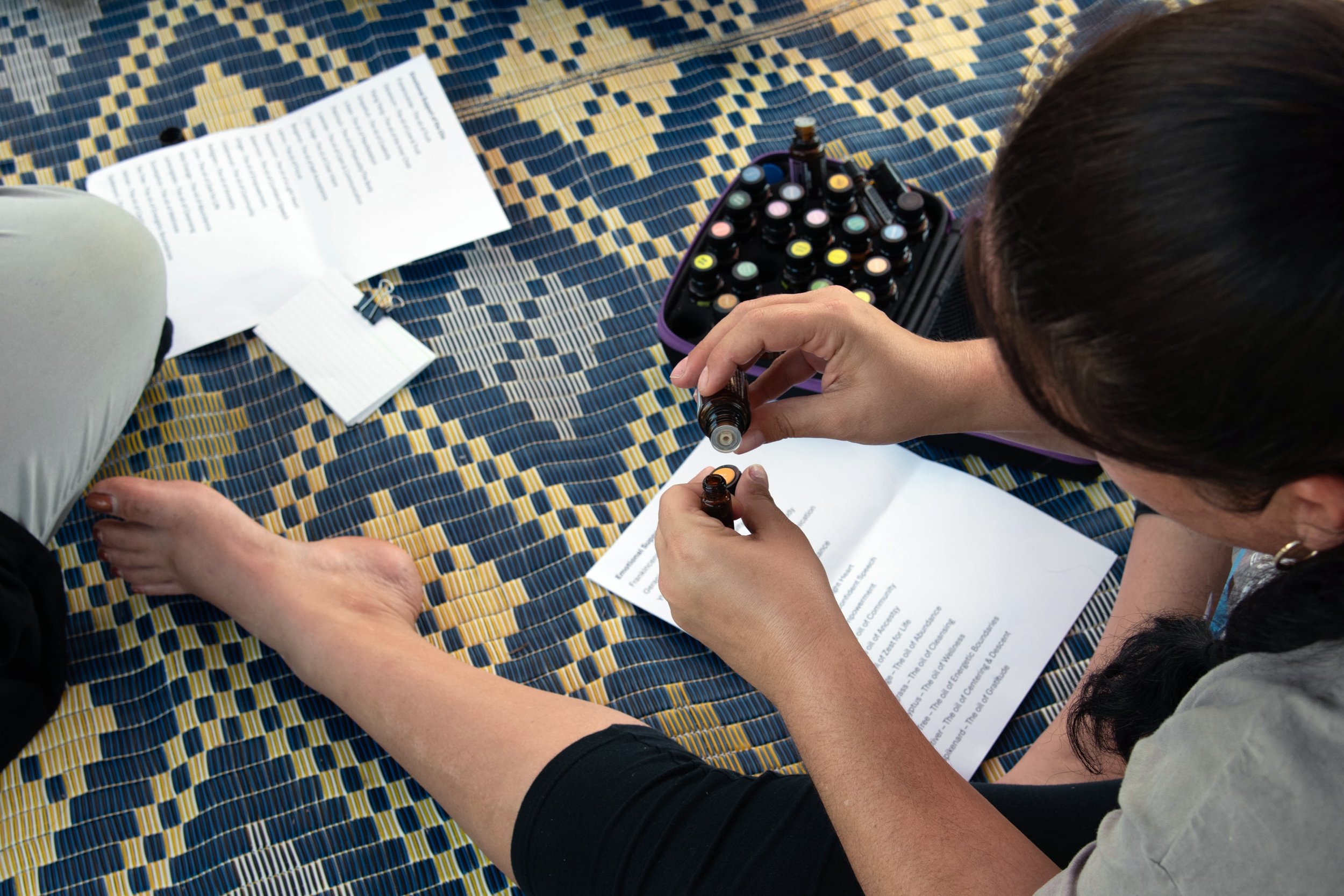 Close-up of woman sitting on a patterned mat, making hand-made business products.