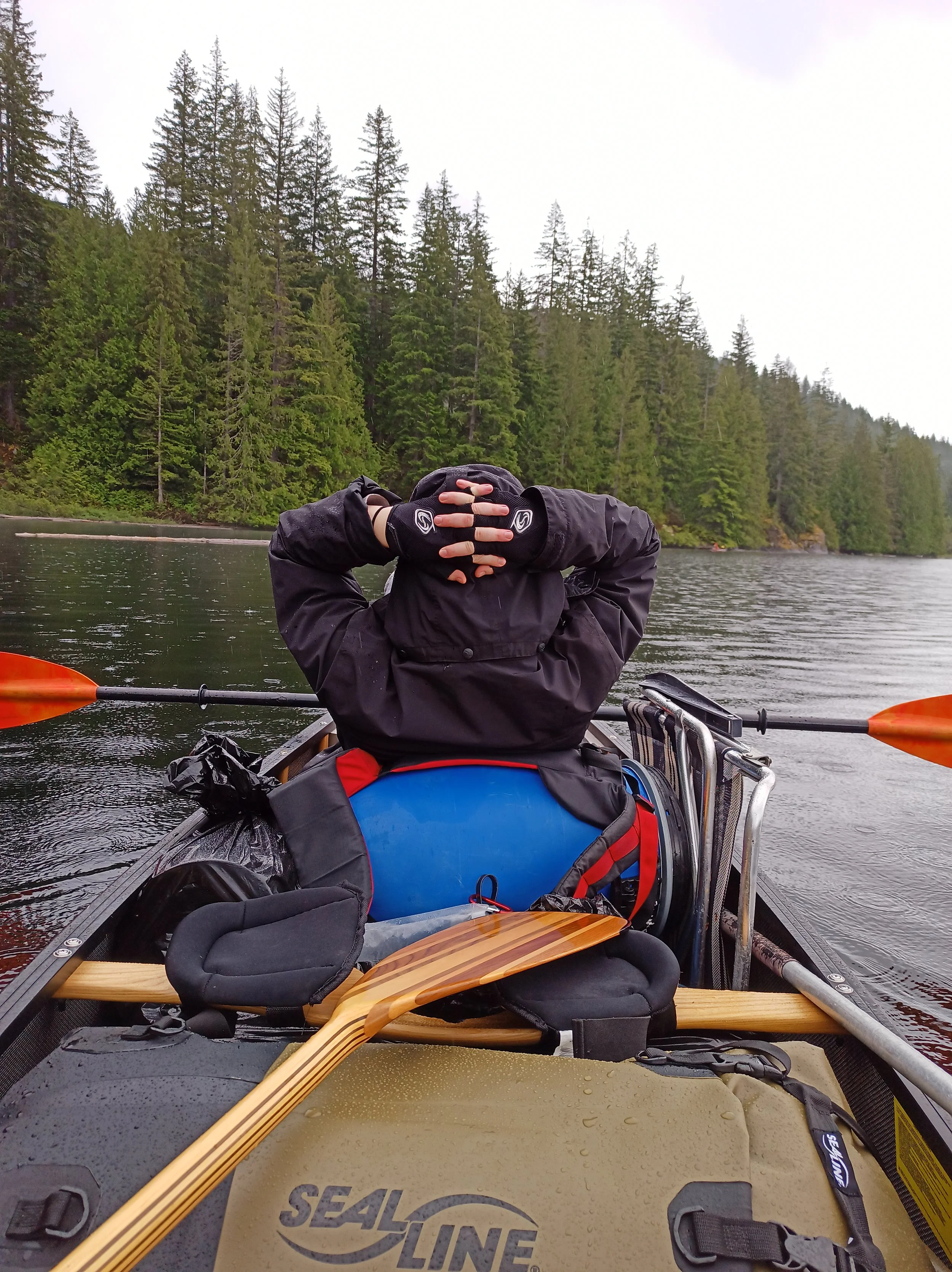 A person in the bow of a canoe, resting his back on gear