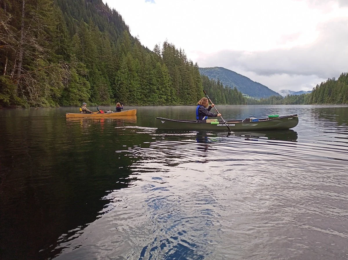 People paddling a tandem and a solo canoe