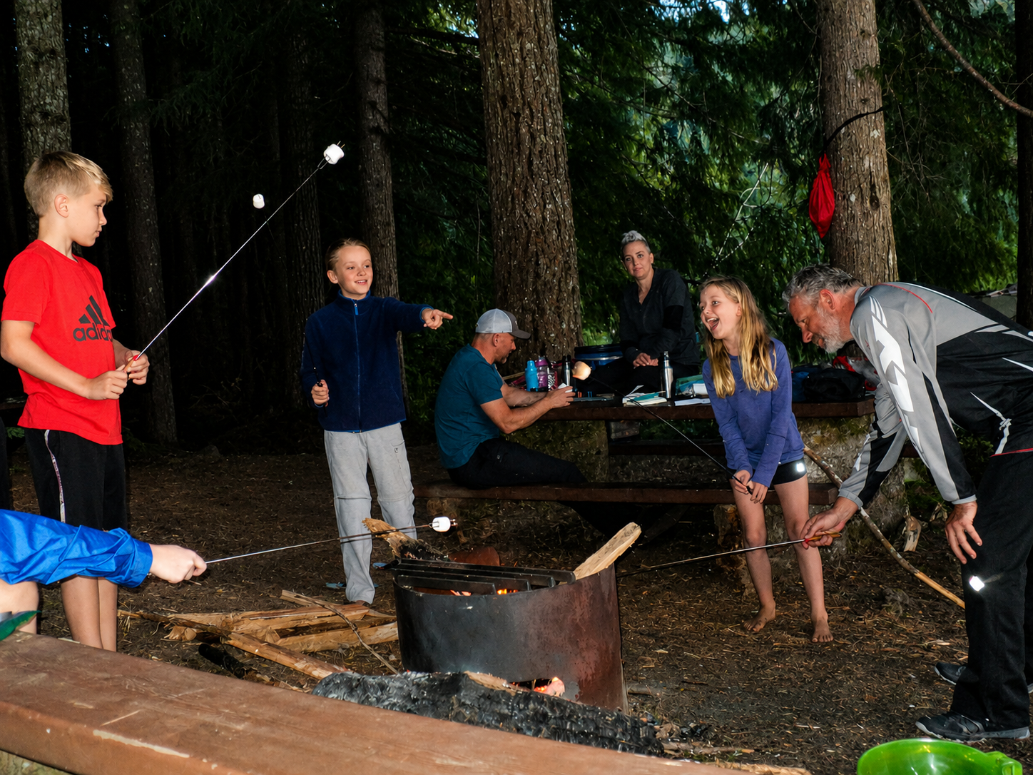 Kids and parents roasting marshmallows over a campfire