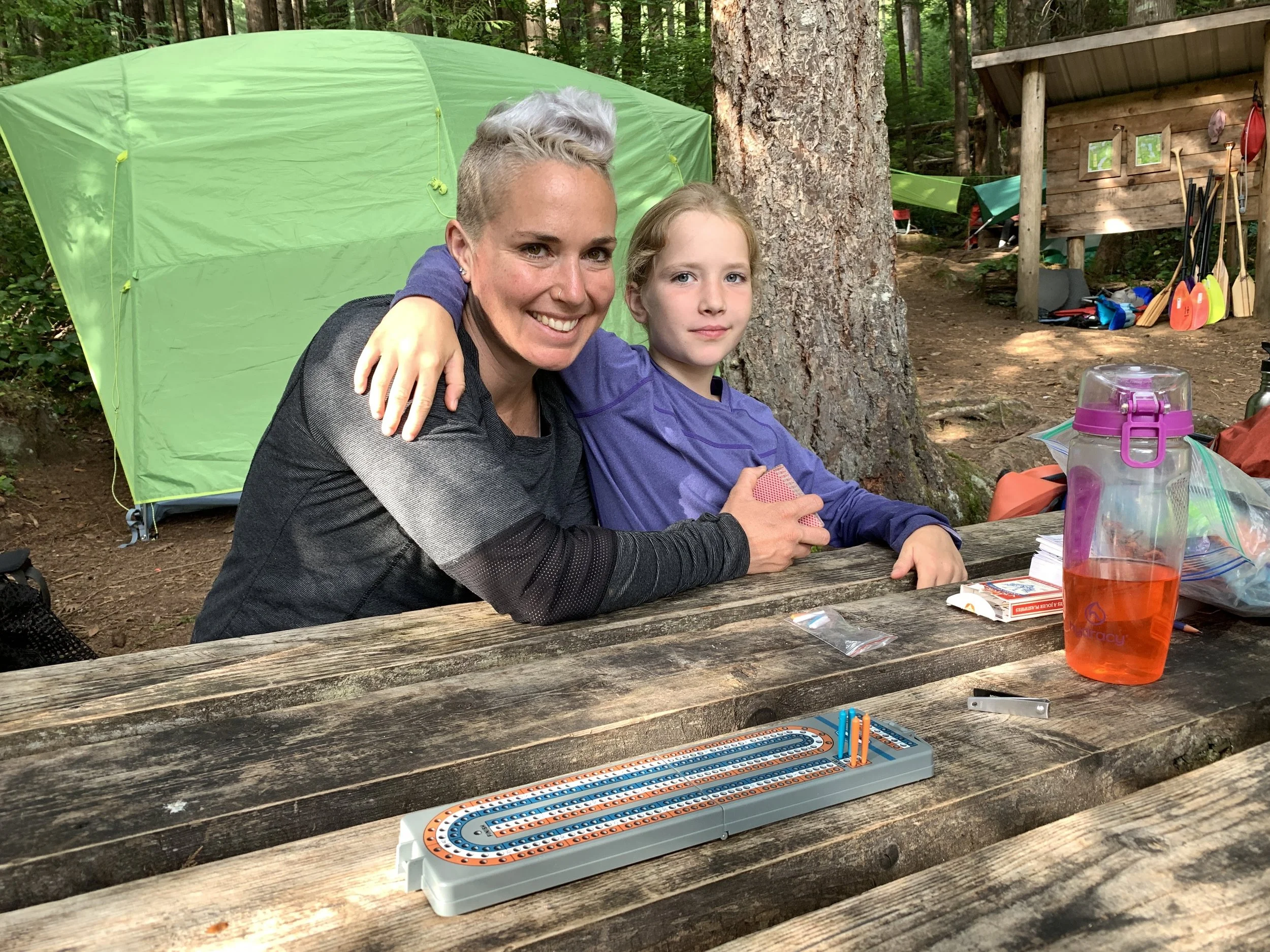 A mother and daughter embracing at the campsite picnic table