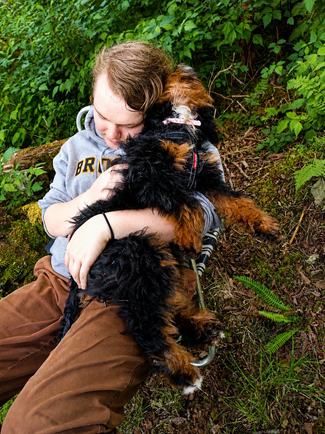 A boy and his puppy cuddling in the forest