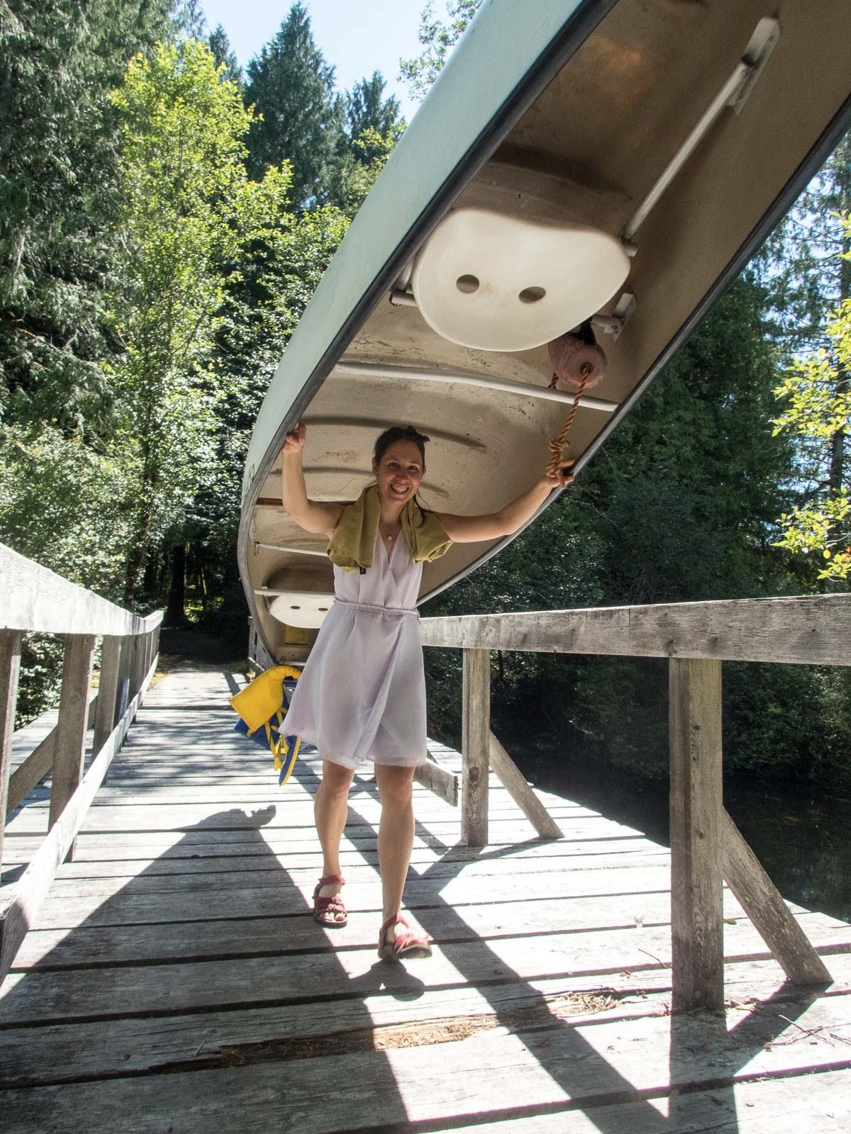 A woman overhead portaging a canoe on a trail