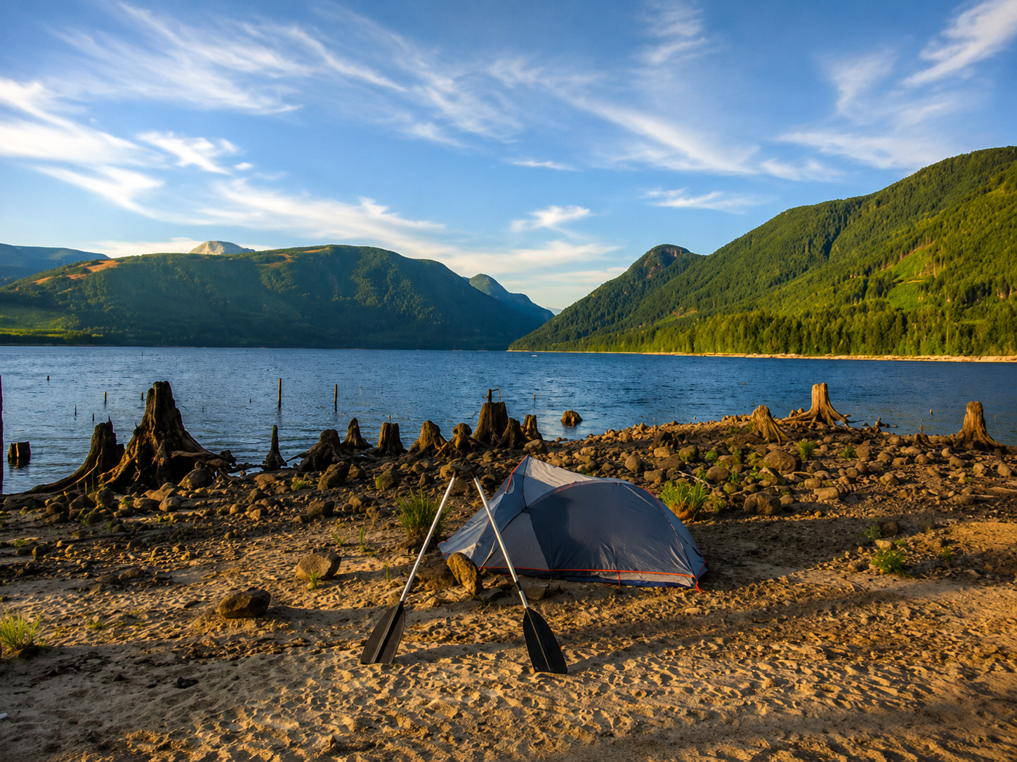 A pitched tent on a lake island, mountains in the background.