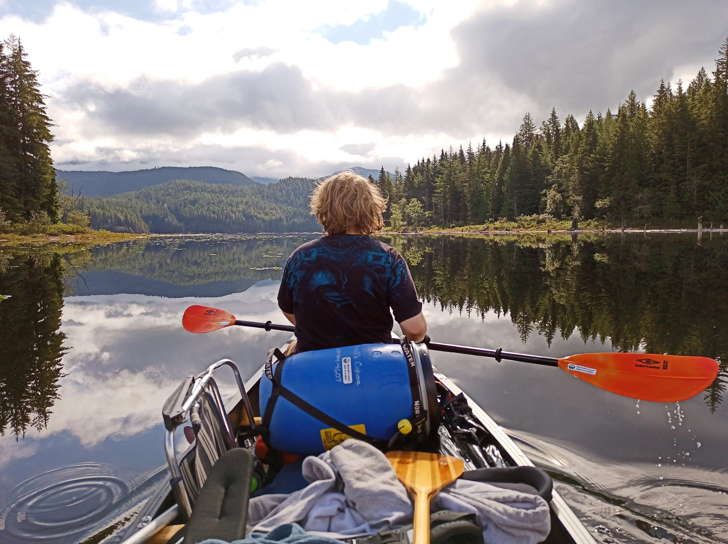 A boy in the bow seat, paddling a loaded canoe