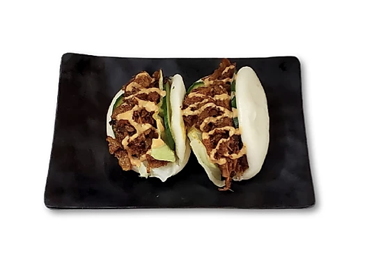 Two bao buns with fillings on a black rectangular plate.