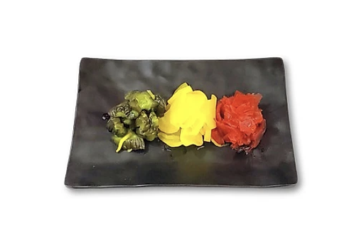 A black plate with three types of Japanese pickles: green, yellow, and red, arranged in a row.