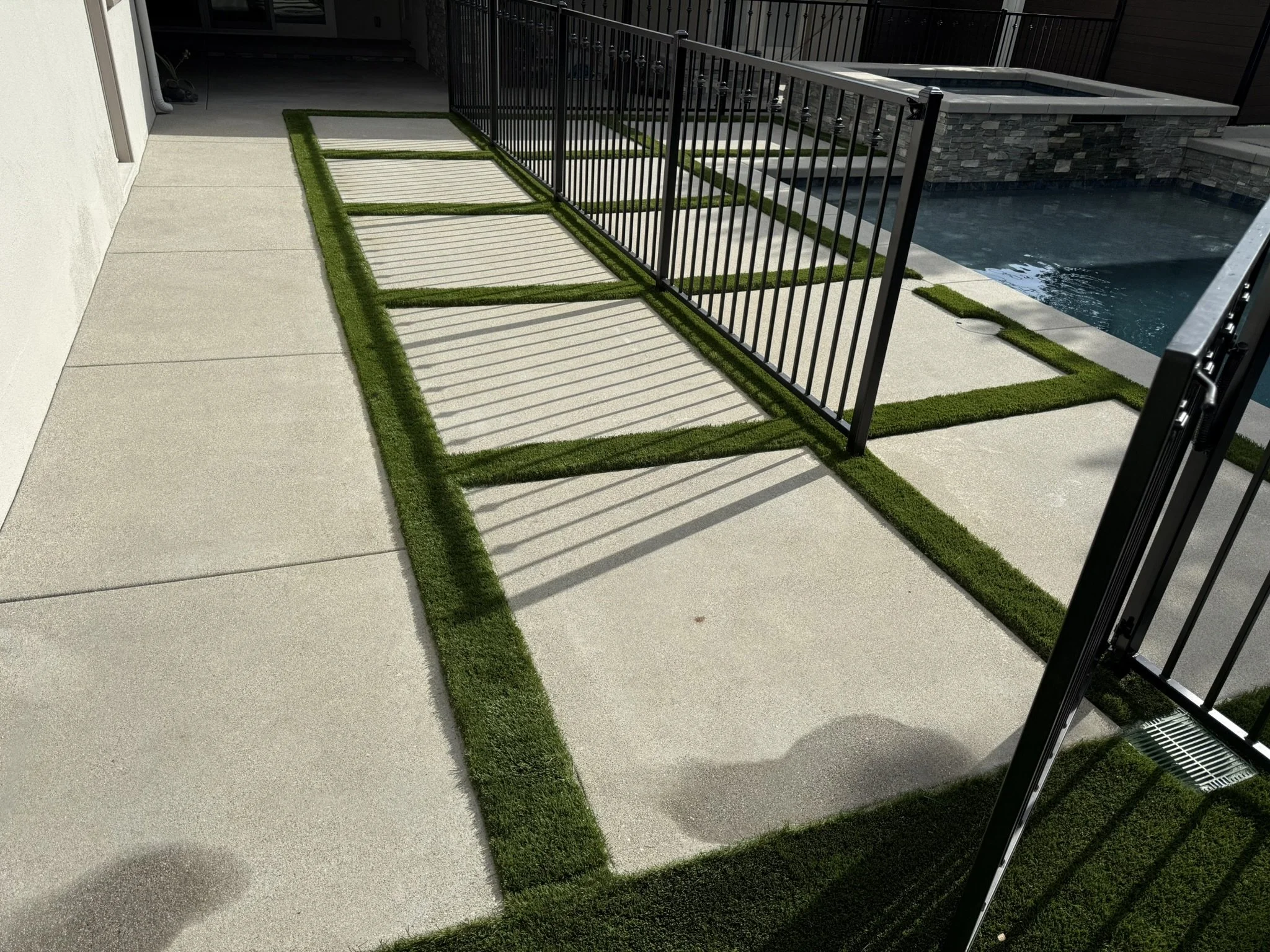 CONCRETE & FLATWORK | Concrete stepping pads with turf joints beside the pool area.