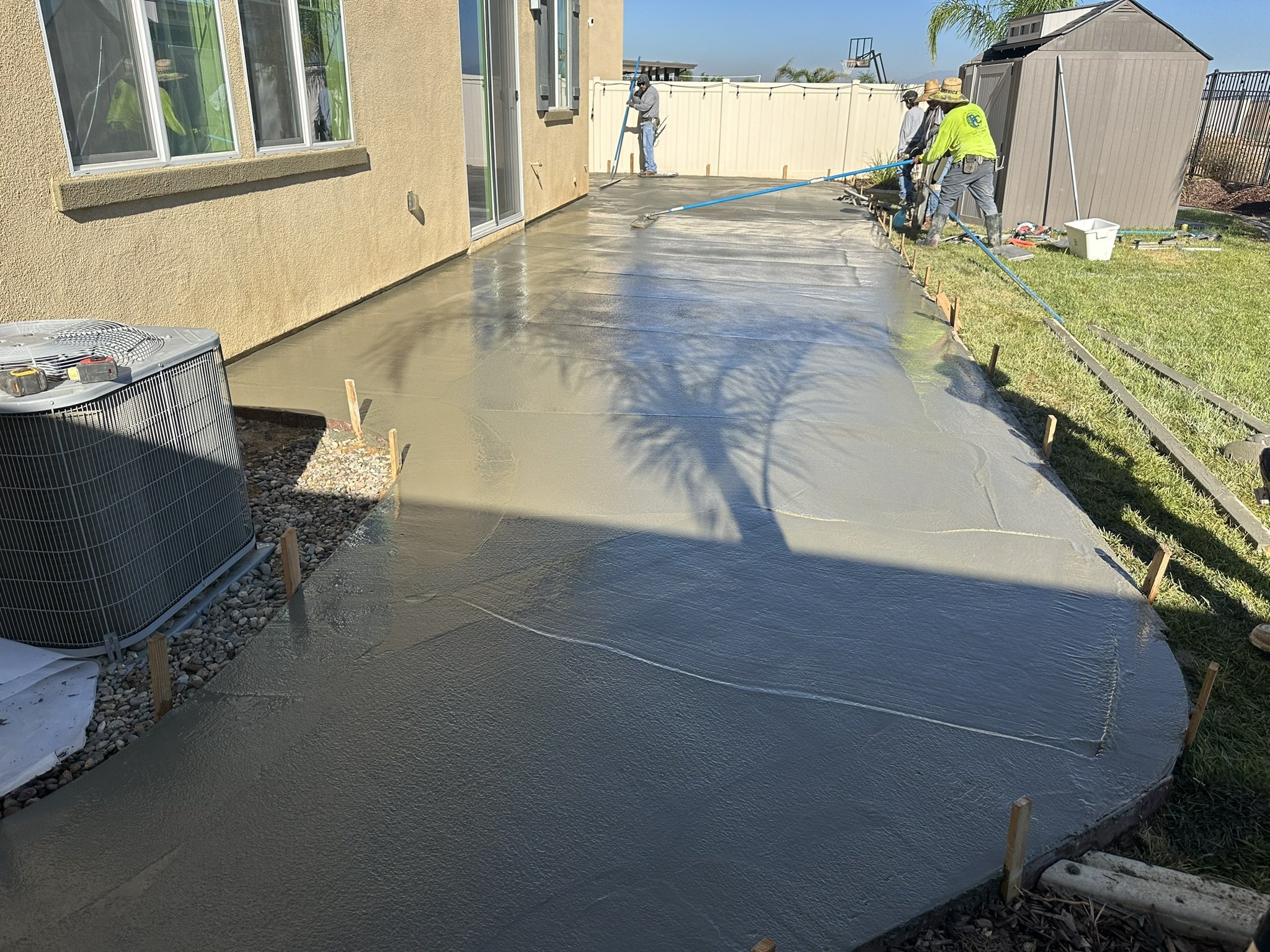 CONCRETE & FLATWORK | In progress — placing and finishing concrete beside the home.
