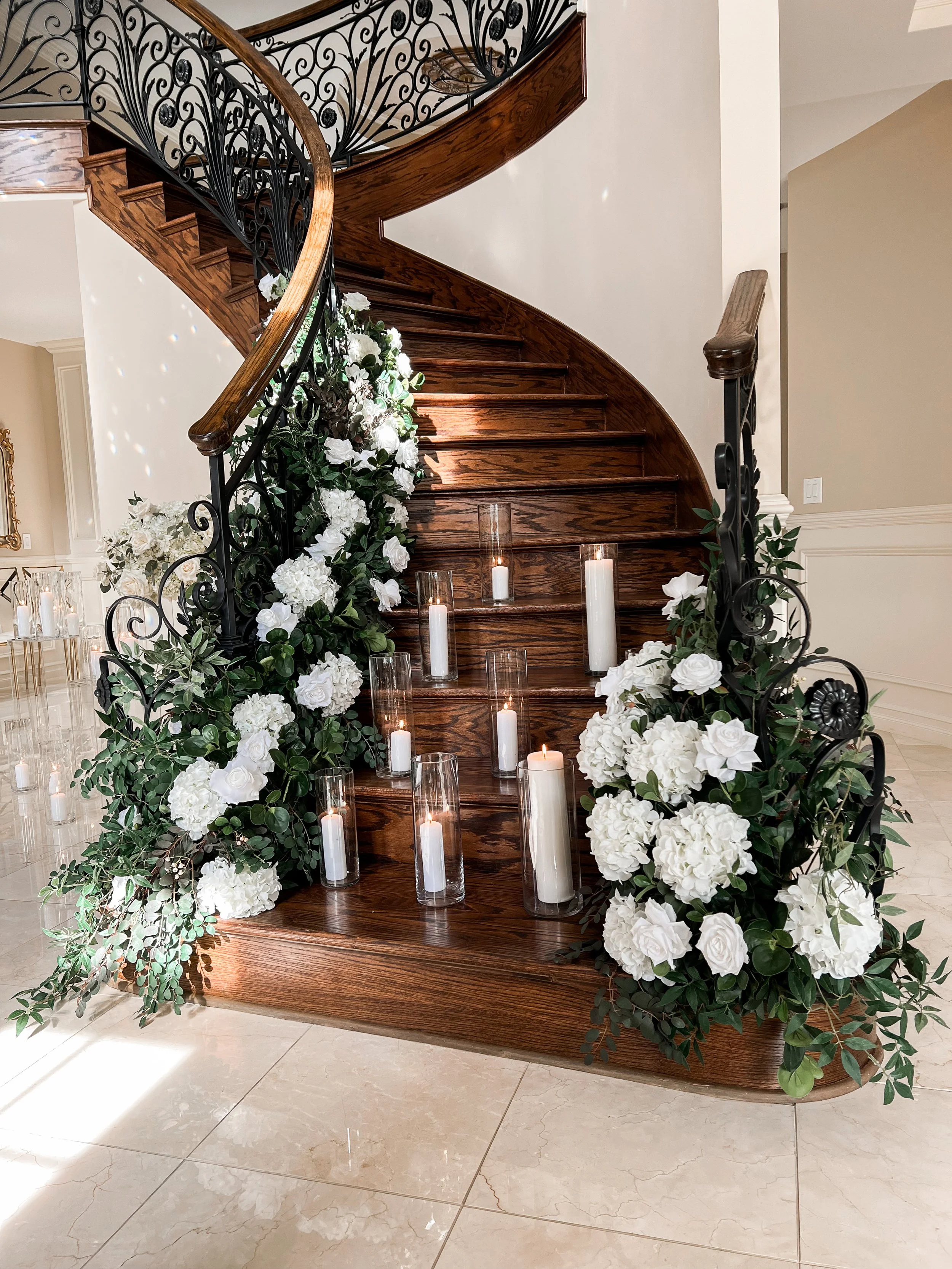 Decorated staircase with white flowers and candles in glass holders.