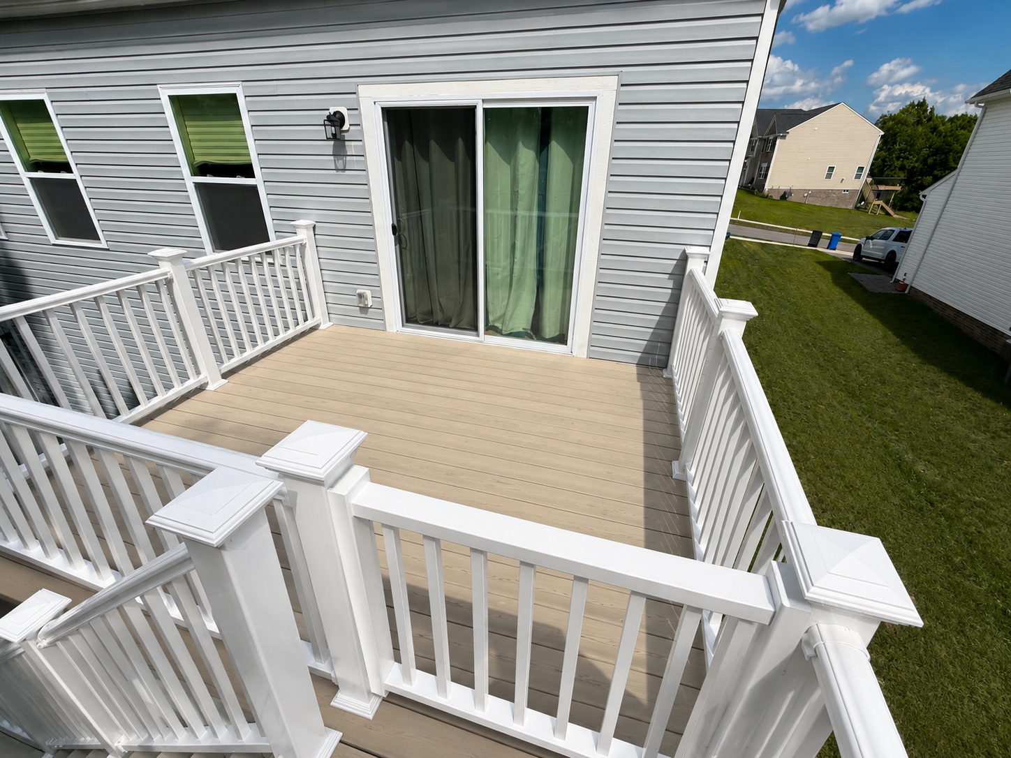 Completed residential deck and patio renovation project in North Huntingdon, Pennsylvania. This image showcases a newly constructed concrete patio, rebuilt elevated deck with a staircase, white vinyl railing, and a finished outdoor living space compl