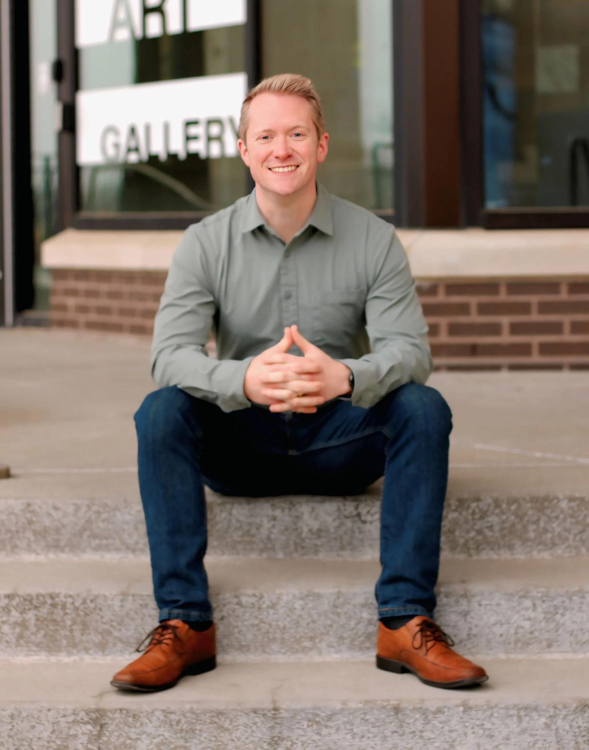 John Michael Handley dressed professionally sitting in front of city hall.