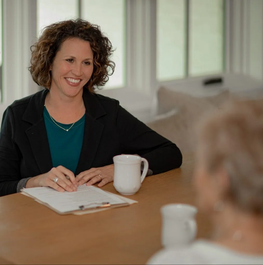 Whitney meeting with a family, sitting at a table with white coffee cups in front of them
