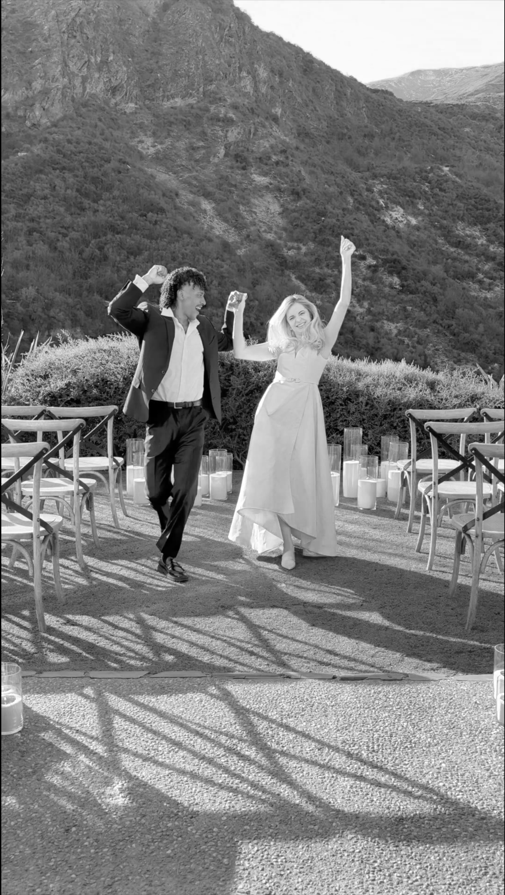 A couple celebrating outdoors at a wedding or special event, dancing with mountains in the background and candles on the ground. content creator queenstown