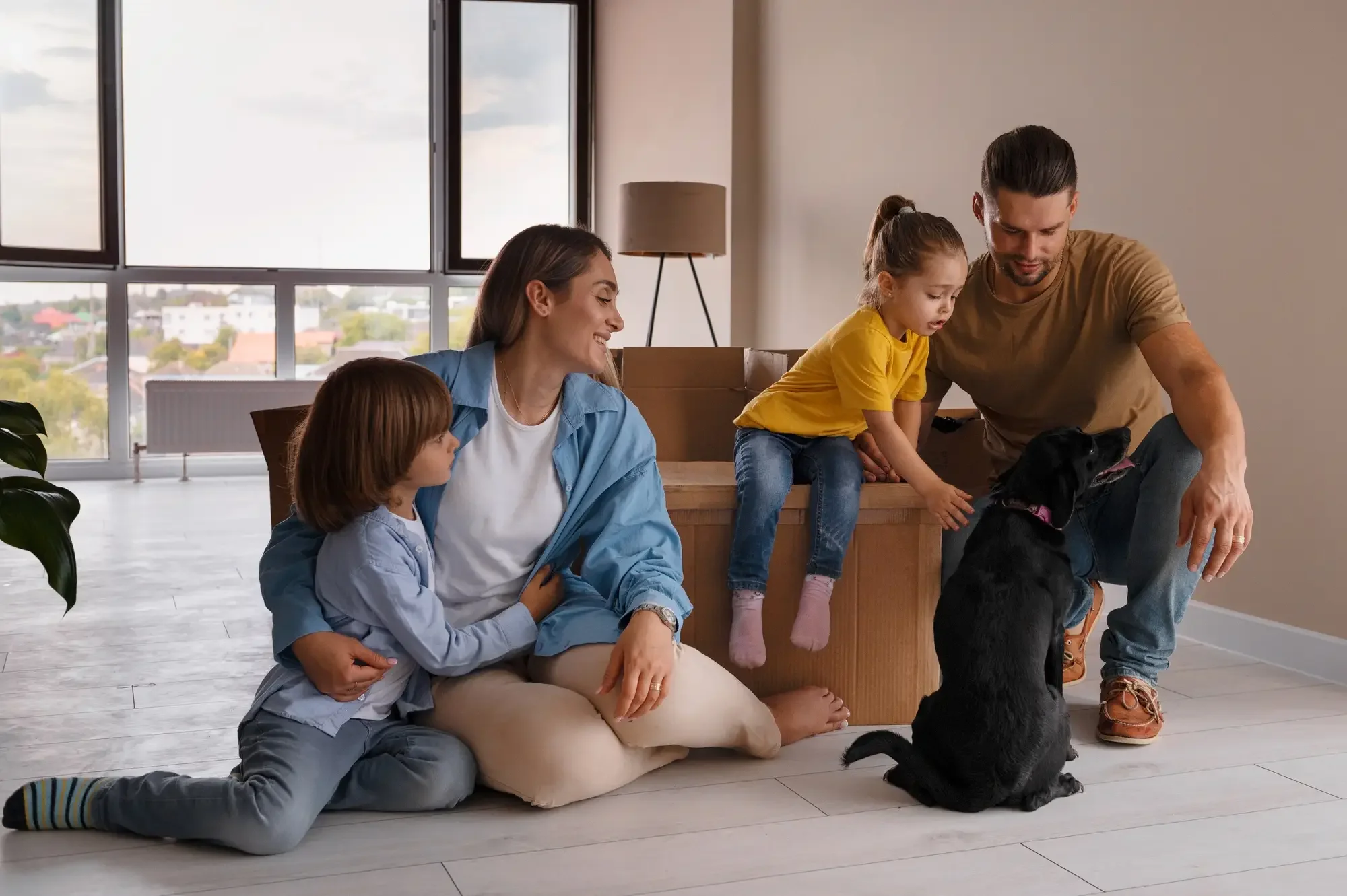 a small family of 4 playing with their pet after moving