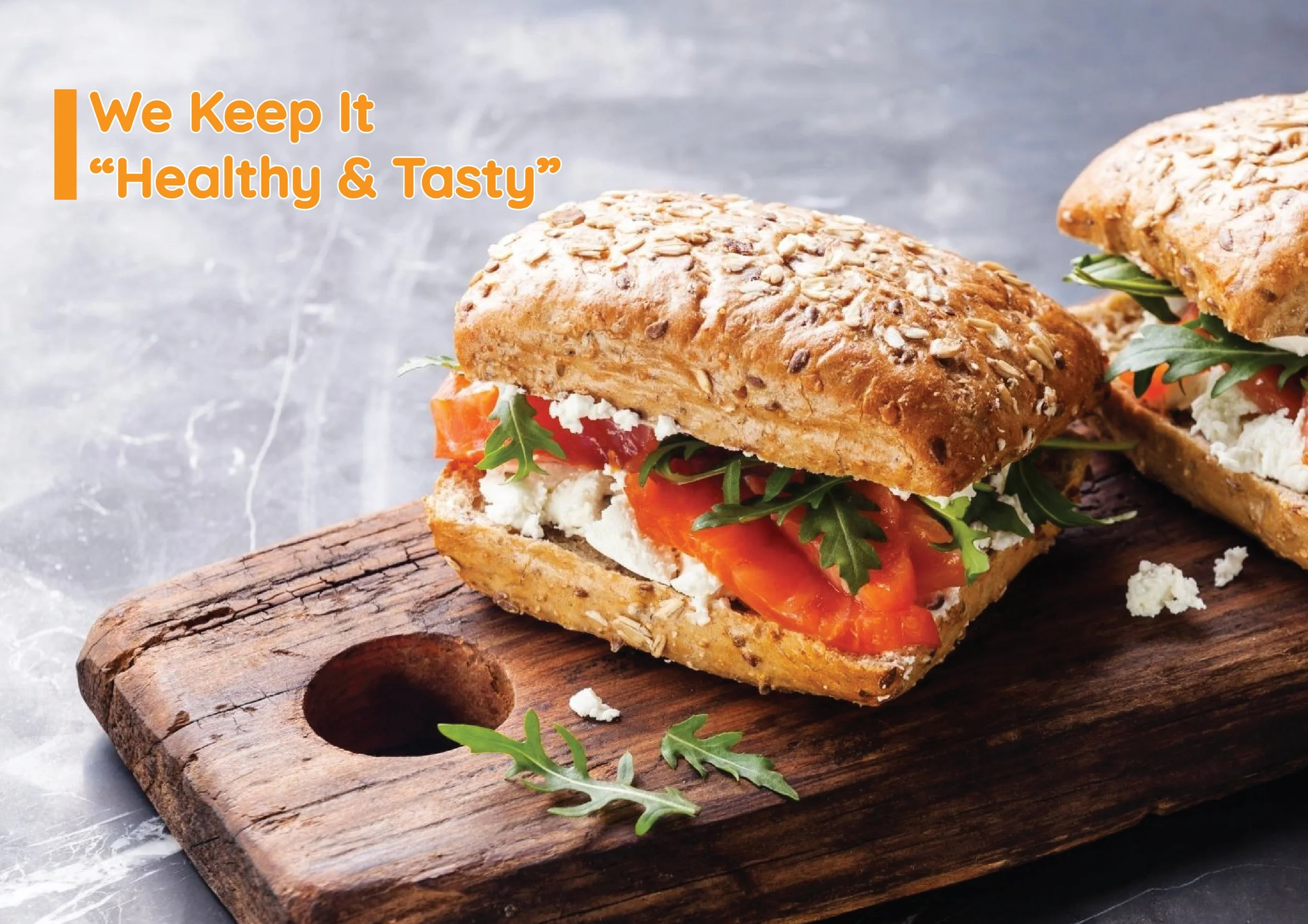 Tam tahıllı ekmekle yapılmış, içinde peynir, domates ve roka olan sandviç. Üzerinde 'We Keep It Healthy & Tasty' yazılı.