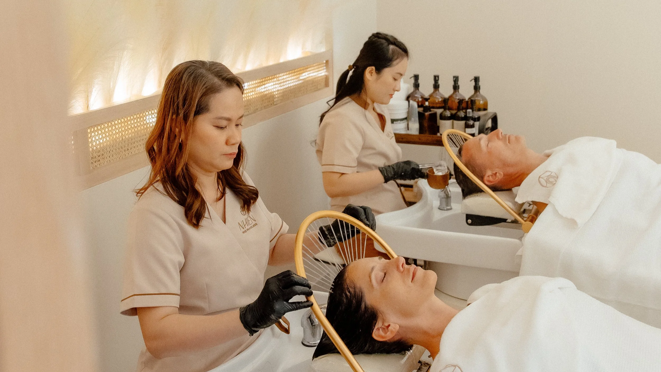 A person relaxing with their eyes closed during a facial or scalp treatment at a spa or wellness center.