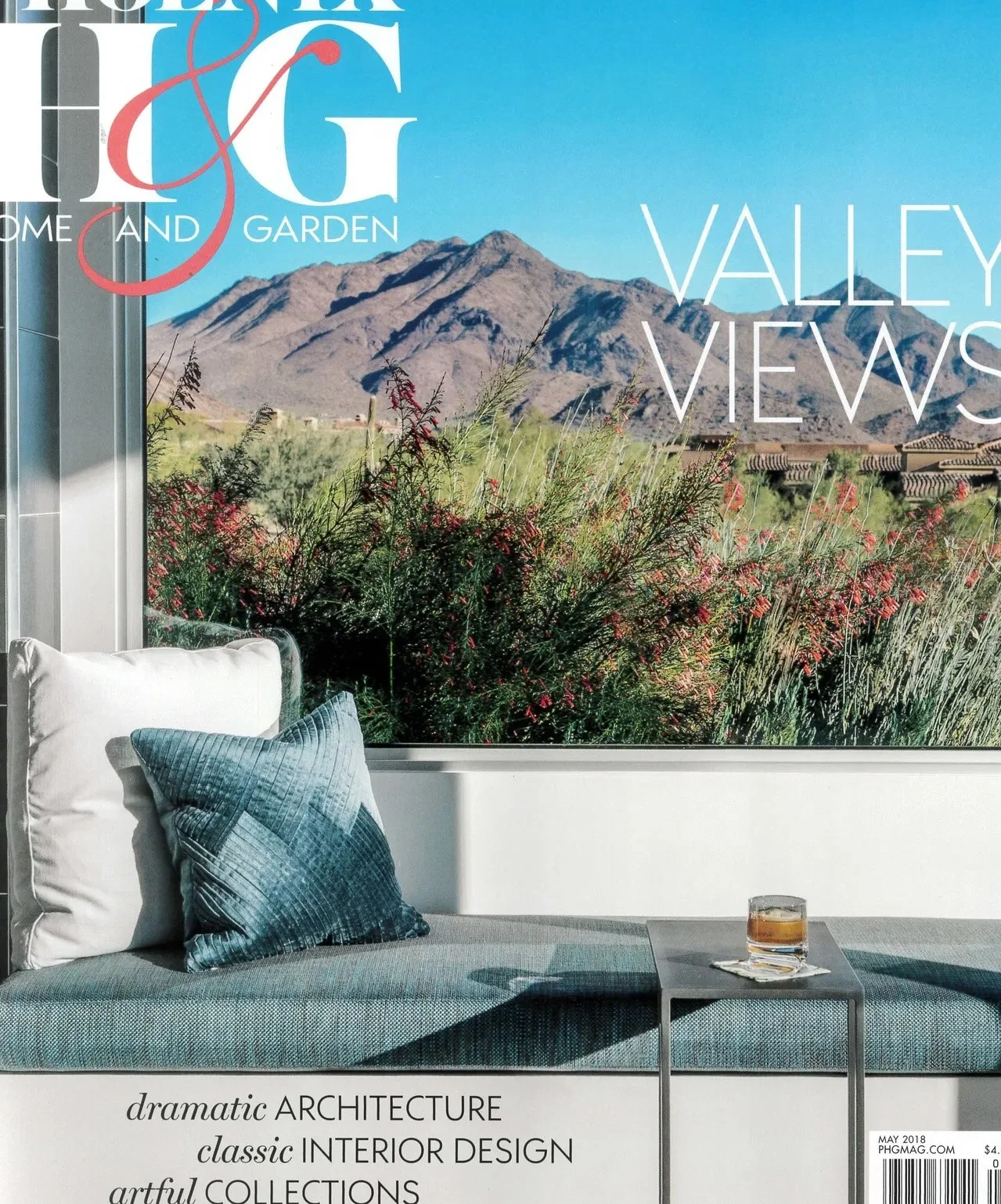 Magazine cover featuring a patio with a view of desert mountains, a modern outdoor bench with pillows, a table with a drink, and text promoting architecture and design.