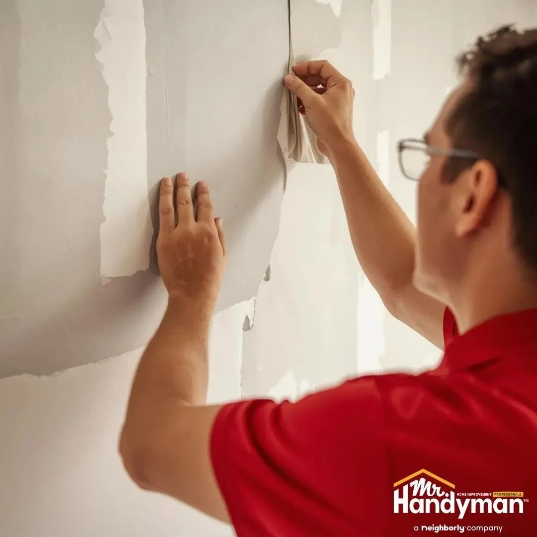Mr. Handyman technician repairing and patching damaged interior drywall for a smooth paint-ready finish.