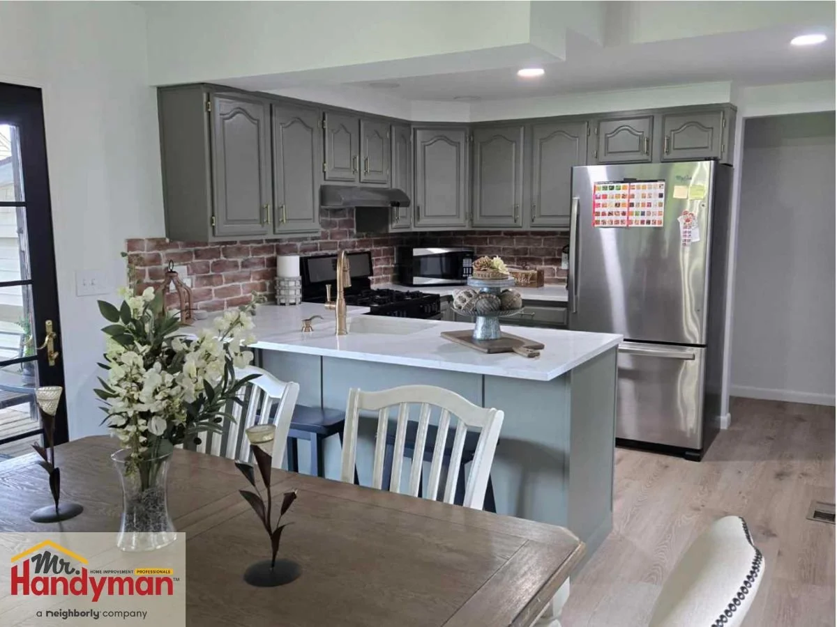 Modern kitchen remodel by Mr. Handyman of Easton, Bethlehem, Nazareth & Allentown, featuring gray cabinets, brick backsplash, quartz countertops, and stainless steel appliances.