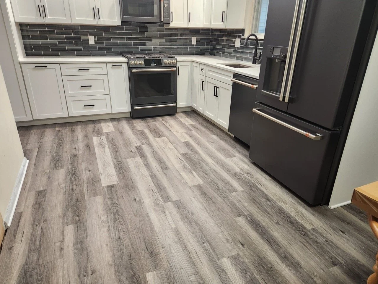 White cabinet kitchen with gray wood-look flooring and black appliances in Bethlehem, PA.