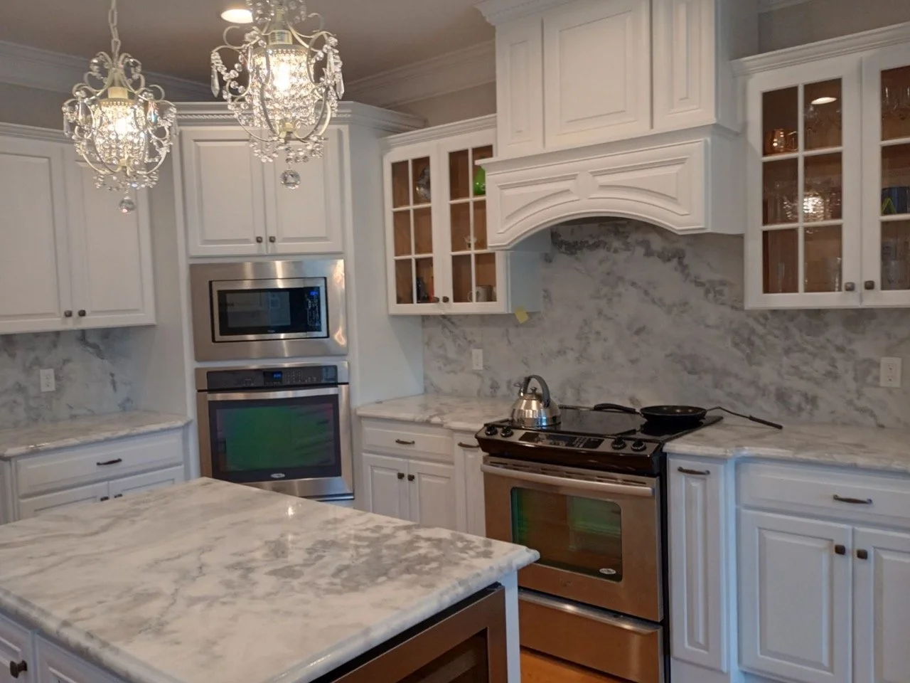 Full view of luxury white kitchen renovation with marble countertops and decorative lighting by Mr. Handyman in Northampton County, PA.