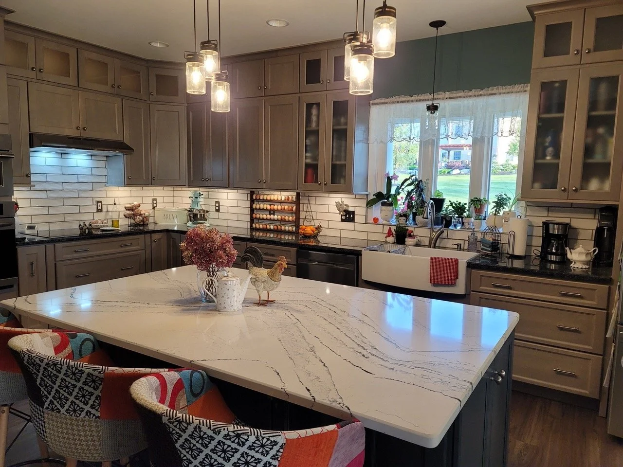 Farmhouse kitchen in Nazareth with glass cabinets, subway tile backsplash, and a large island.