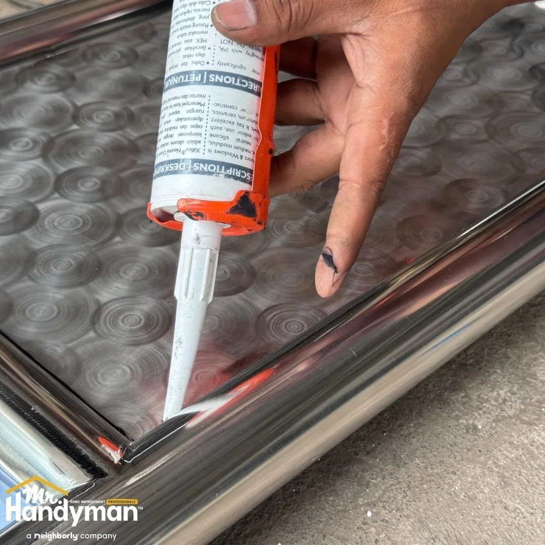 Handyman applying caulk to seal interior glass and metal frame for weatherproofing and draft prevention in Lehigh Valley