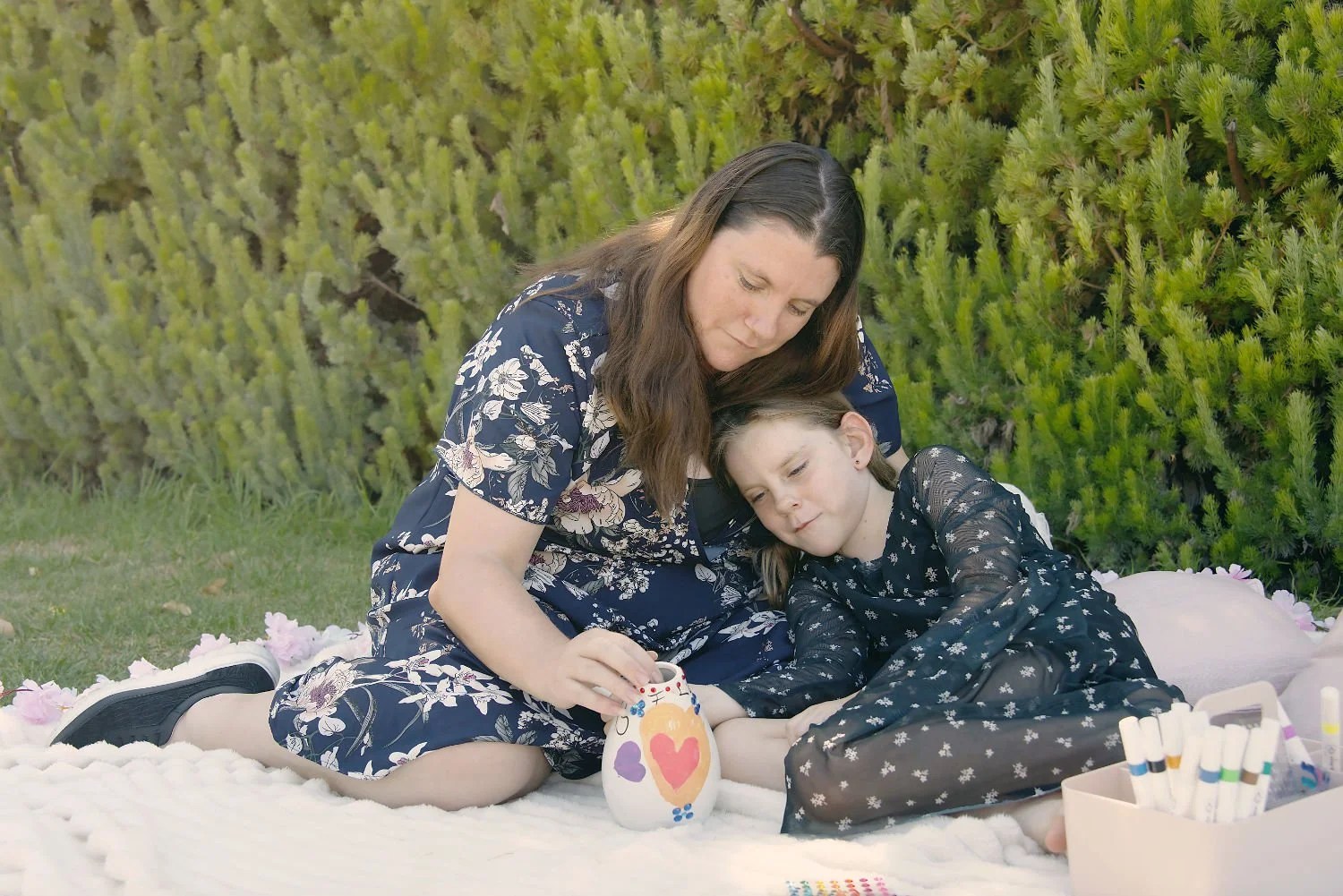 A mother and daughter decorate a vase together
